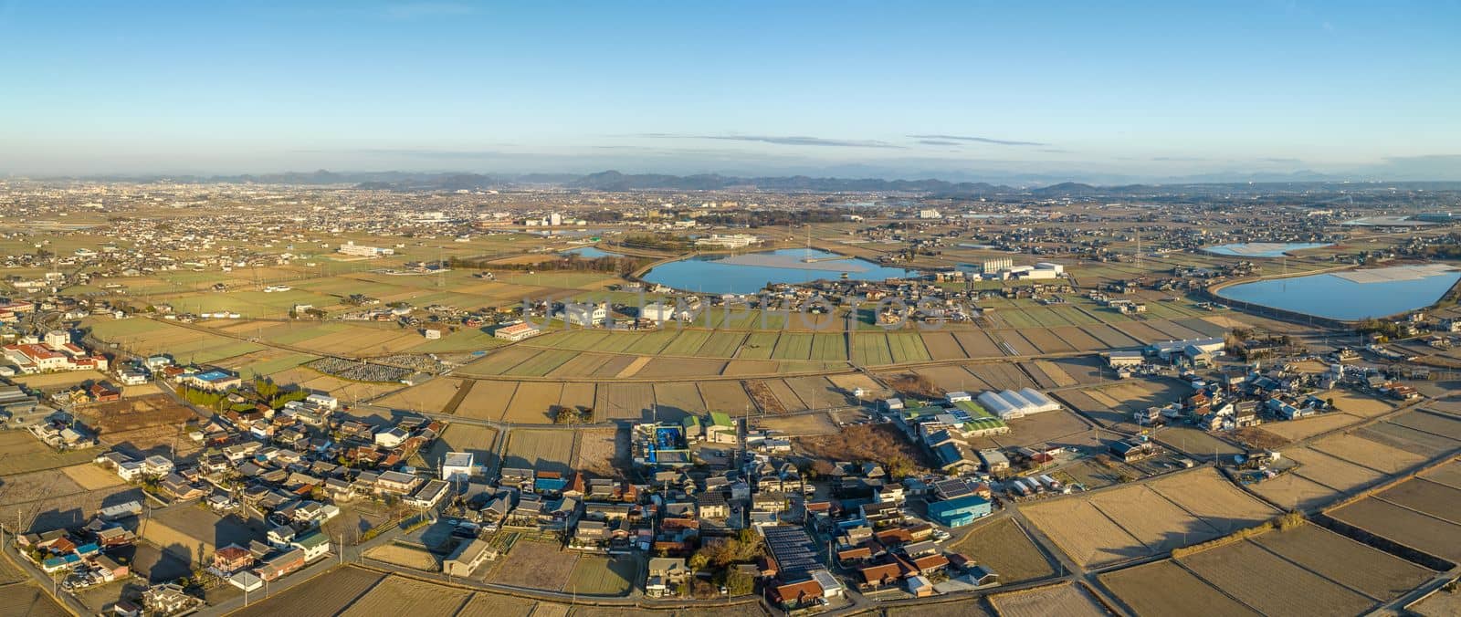 Panoramic aerial view of dry farms by houses and water storage ponds. High quality photo