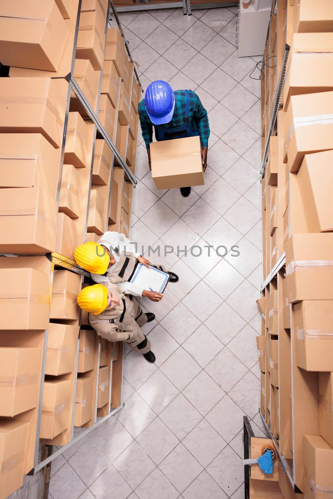 Warehouse employees managing parcels receiving, carrying cardboard box. Diverse man and women retail storehouse managers working and coordinating goods supply chain top view