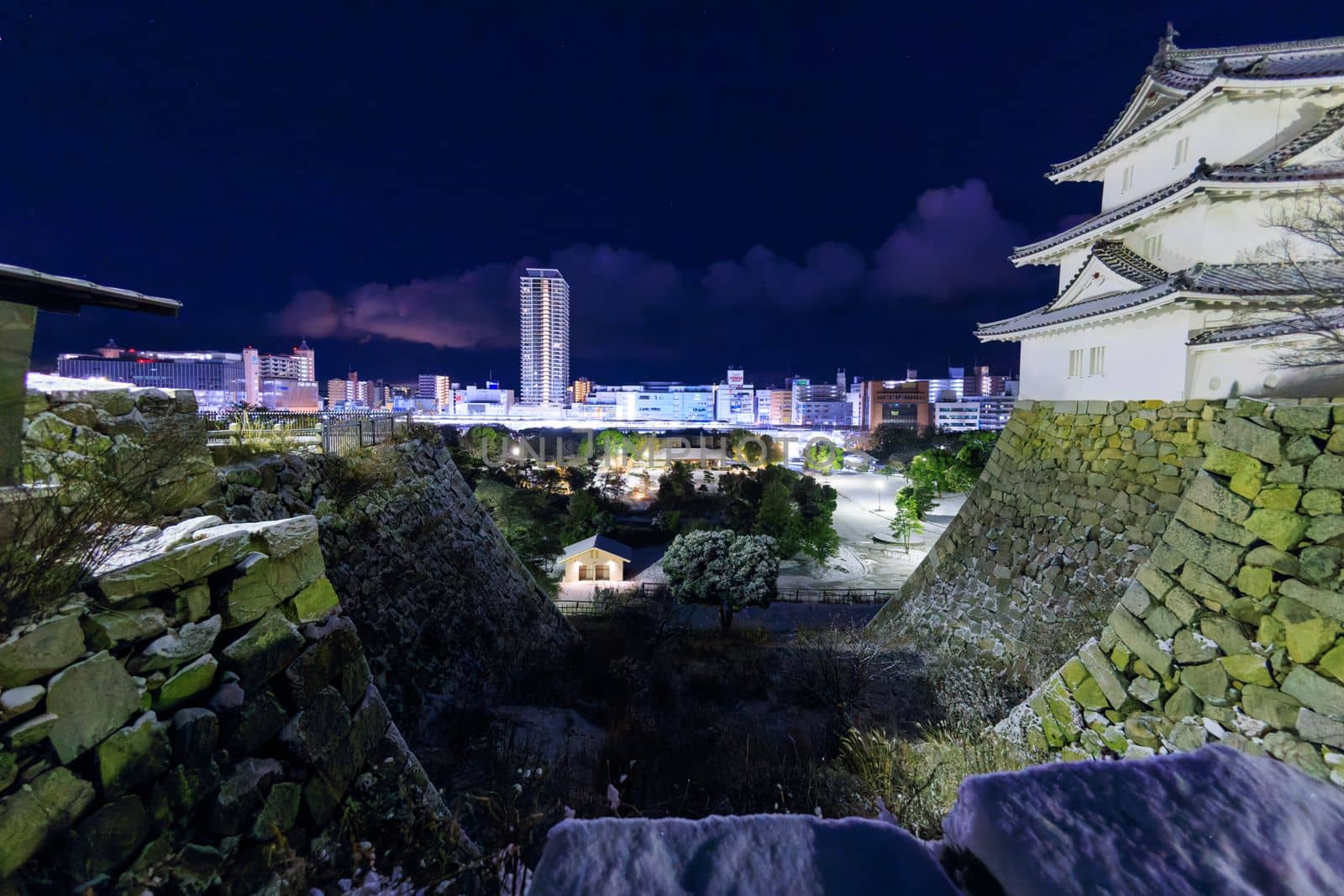 Akashi, Japan - January 25, 2023: Historic Japanese castle towers over city skyline on snowy winter night. High quality photo