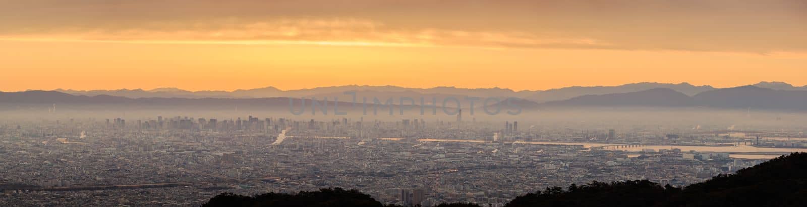Panoramic view of haze layer over city with orange glow in sky at sunrise. High quality photo
