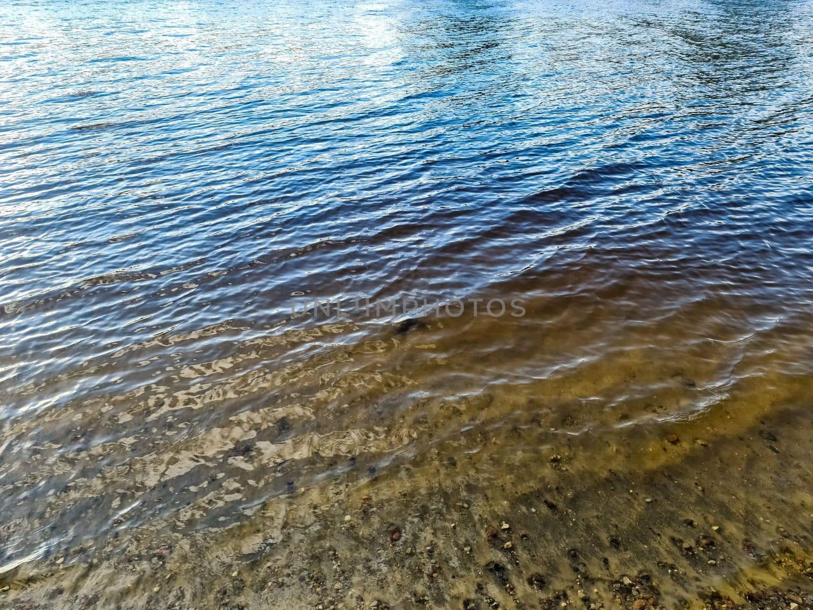 Water surface with waves and ripples and the sunlight reflecting at the surface