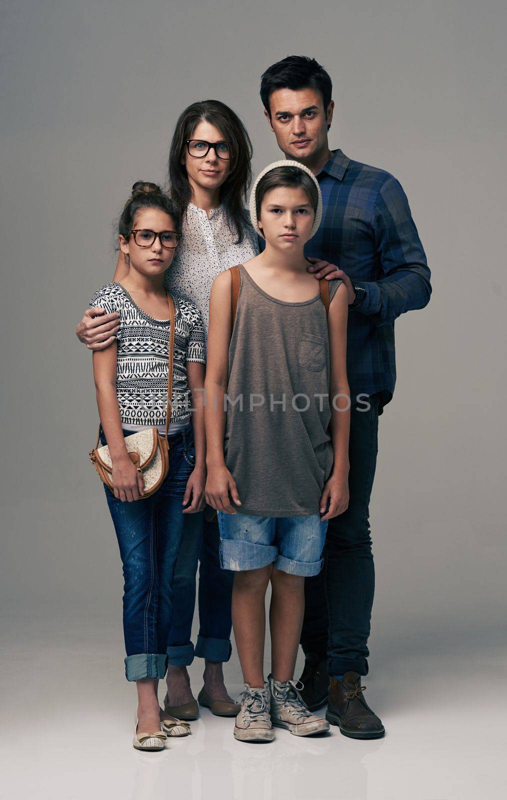 Who says family cant be trendy. Studio shot of trendy young family against a gray background. by YuriArcurs