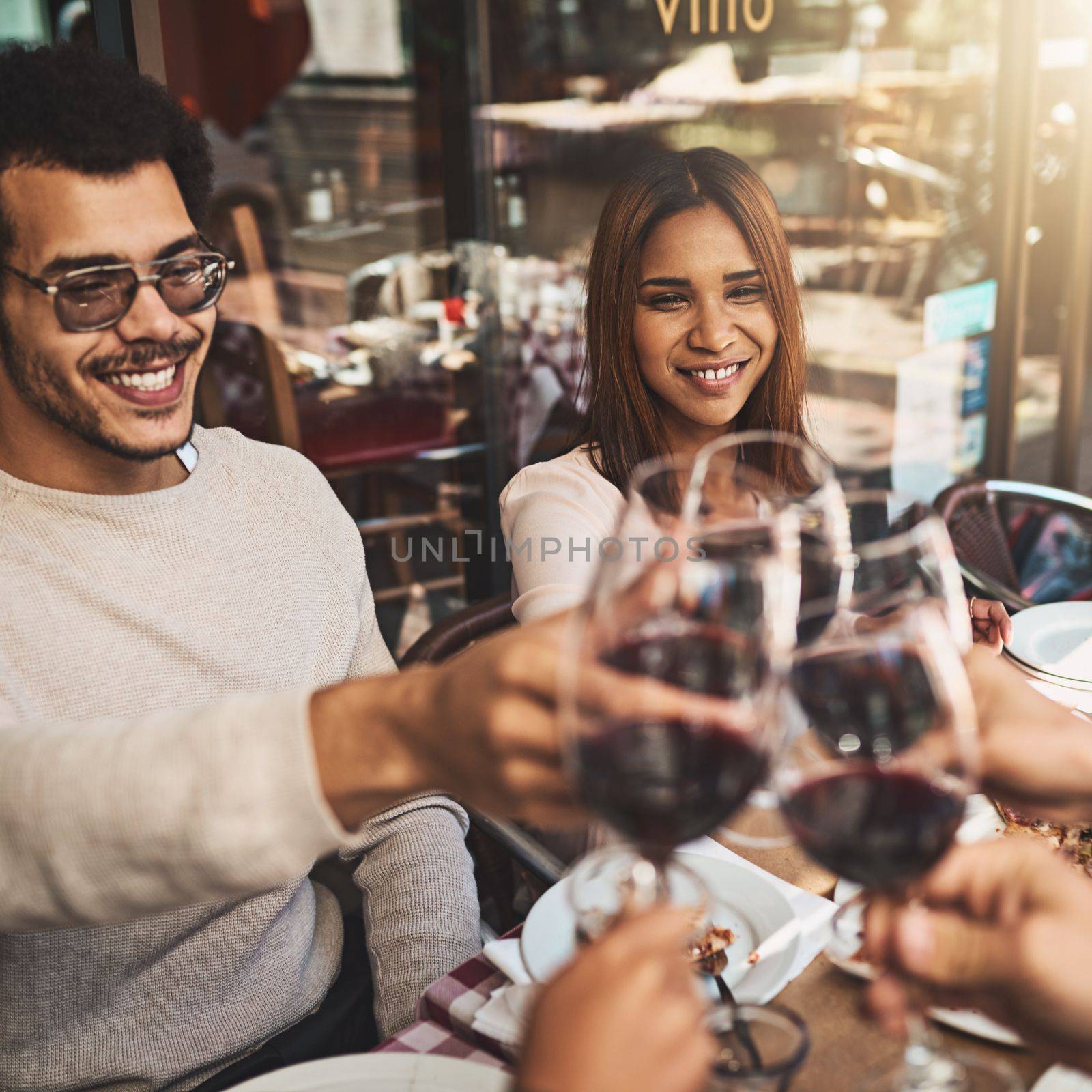 We should do this more often. a group of cheerful young friends having a celebratory toast with wine at dinner inside of a restaurant. by YuriArcurs