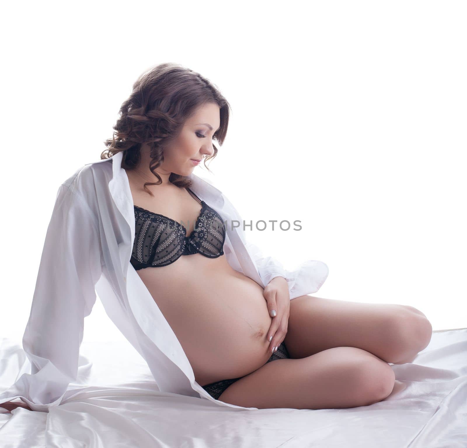 Attractive pregnant brunette posing in studio on white background