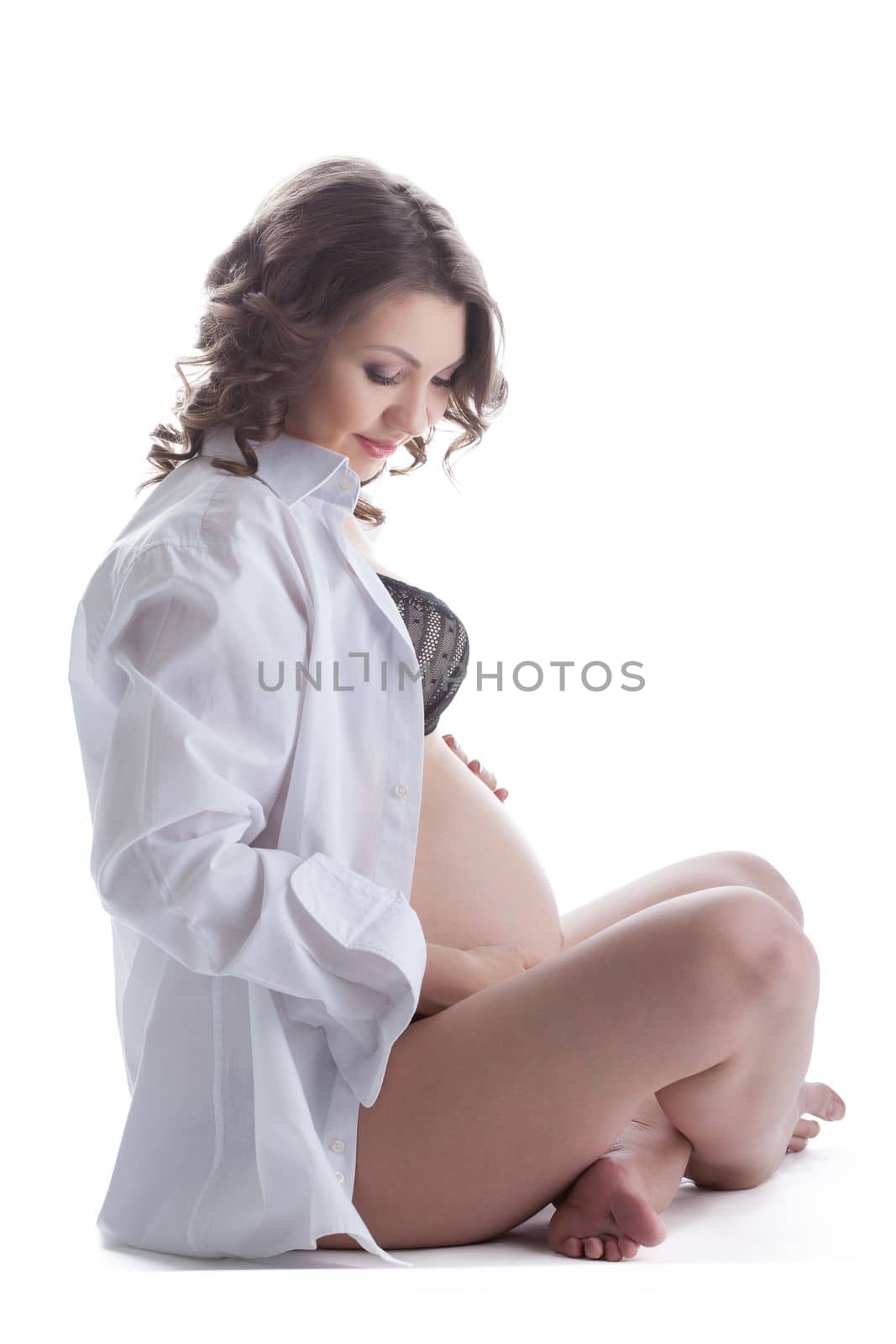 Pregnant woman sitting on floor. Isolated on white