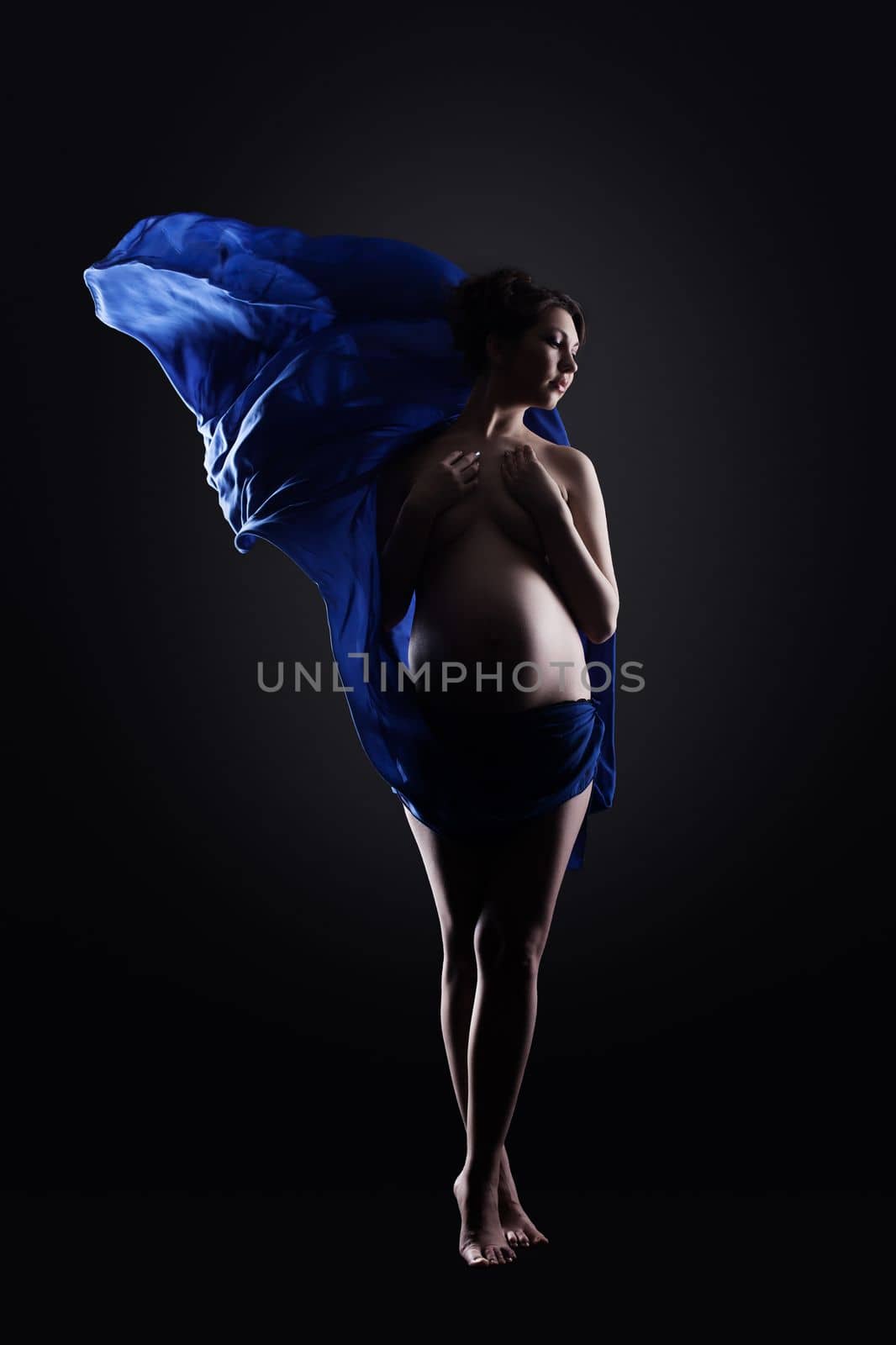 Amazing naked pregnant woman in blue cloth, on gray background