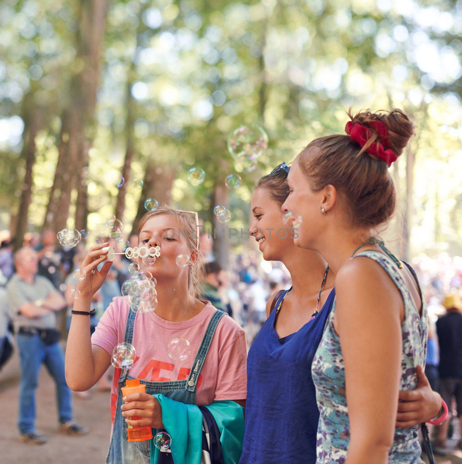 Celebrate your inner child. three young friends blowing bubbles together at an outdoor festival