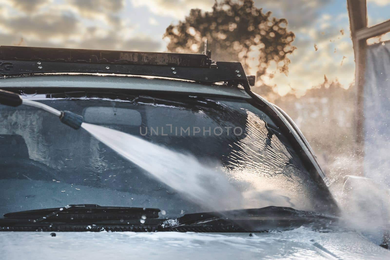 Detail of washing car with high-pressure water hose on car wash service.