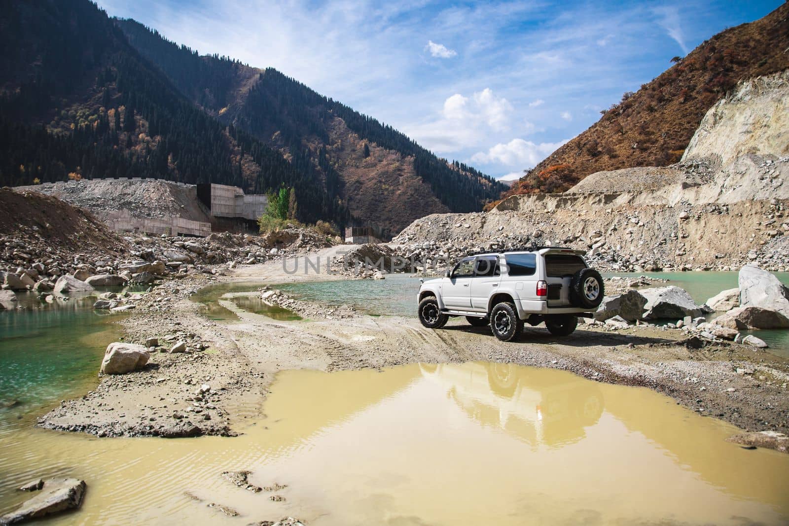 White off-road car in travel of scenic mountains with river and lake.