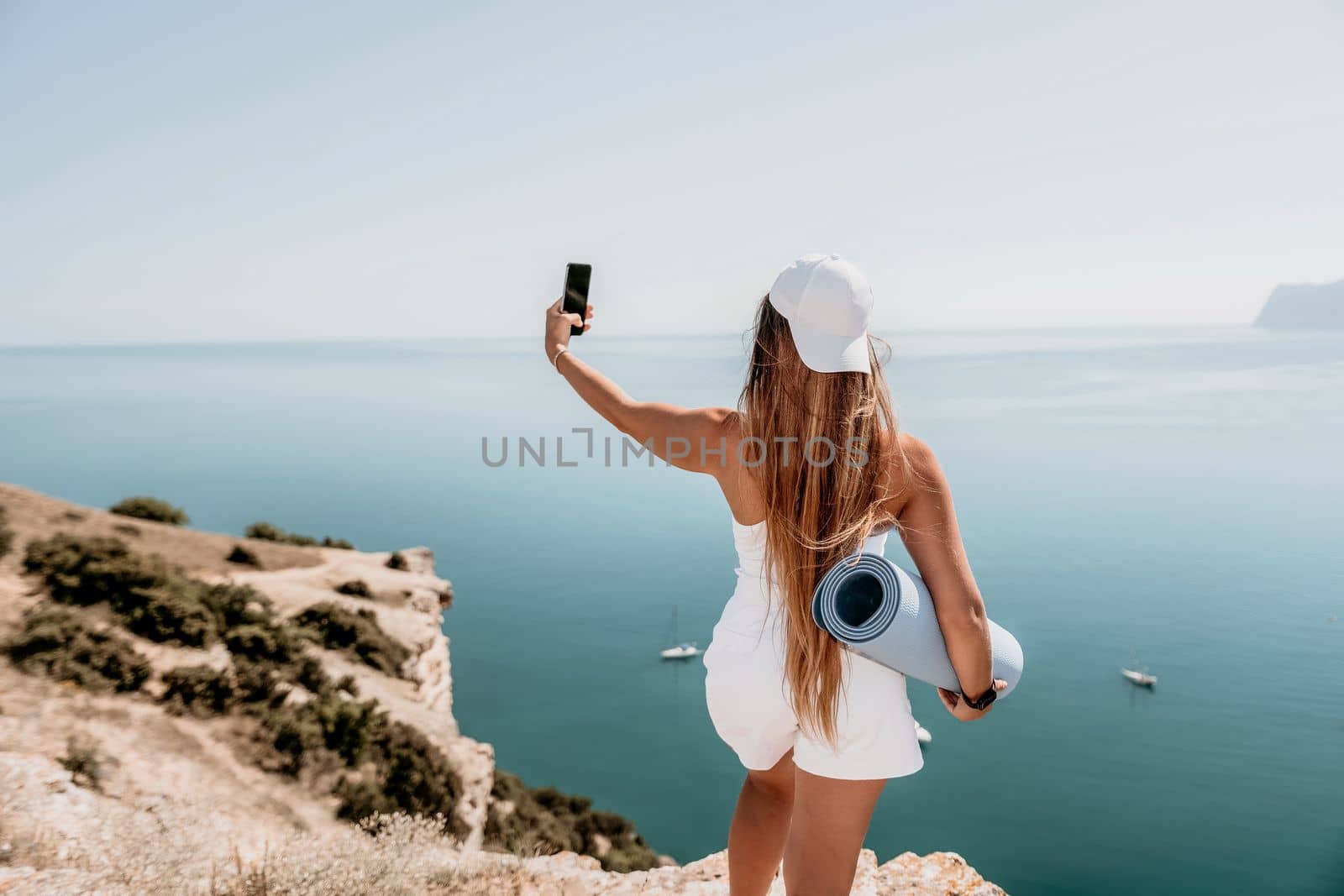 Young woman with black hair, fitness instructor in pink sports leggings and tops, doing pilates on yoga mat with magic pilates ring by the sea on the beach. Female fitness daily yoga concept