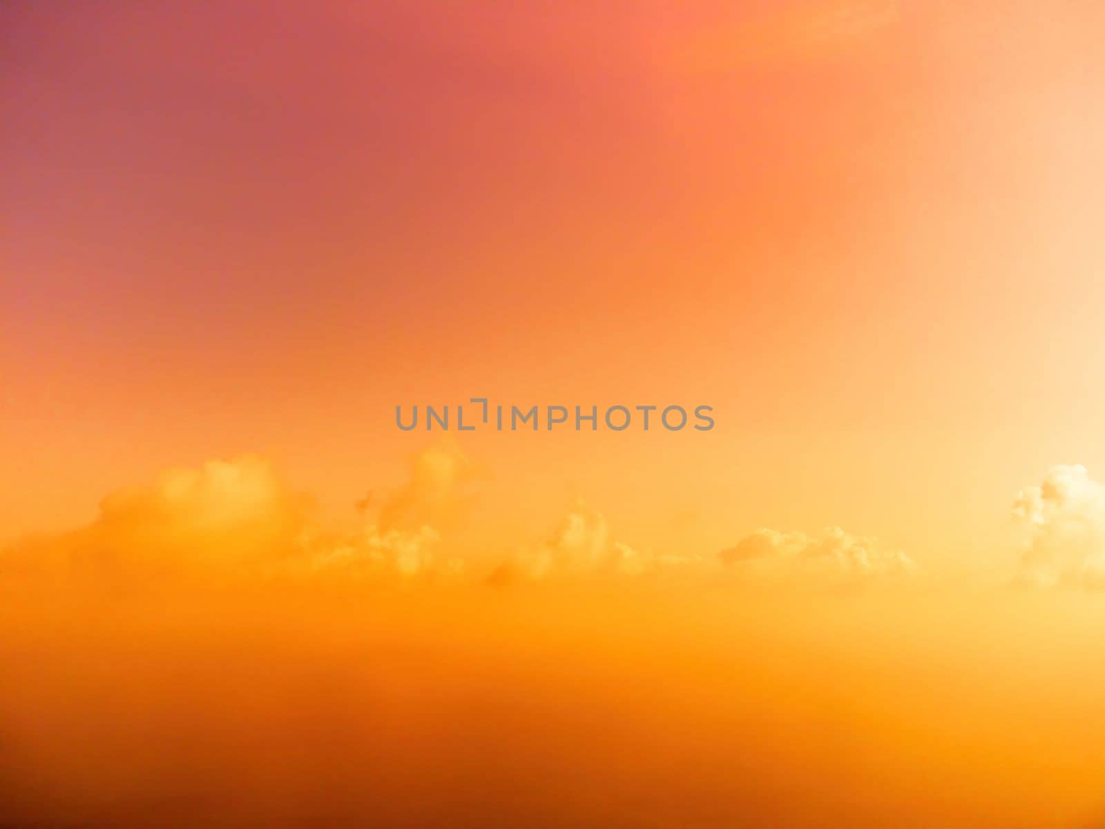 A red burning sunset with the silhouette of a cliff over the sea. Abstract nature summer or spring ocean sea background. Small waves on golden warm water surface with bokeh lights from sun.