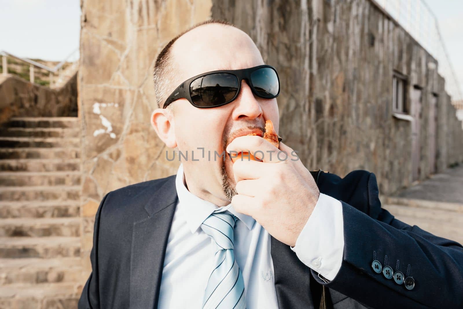 Male persimmon park. Hipster millennial man in a tie and jacket bites off a persimmon while sitting on a park bench in slow motion Young business people eat golden persimmons at lunchtime
