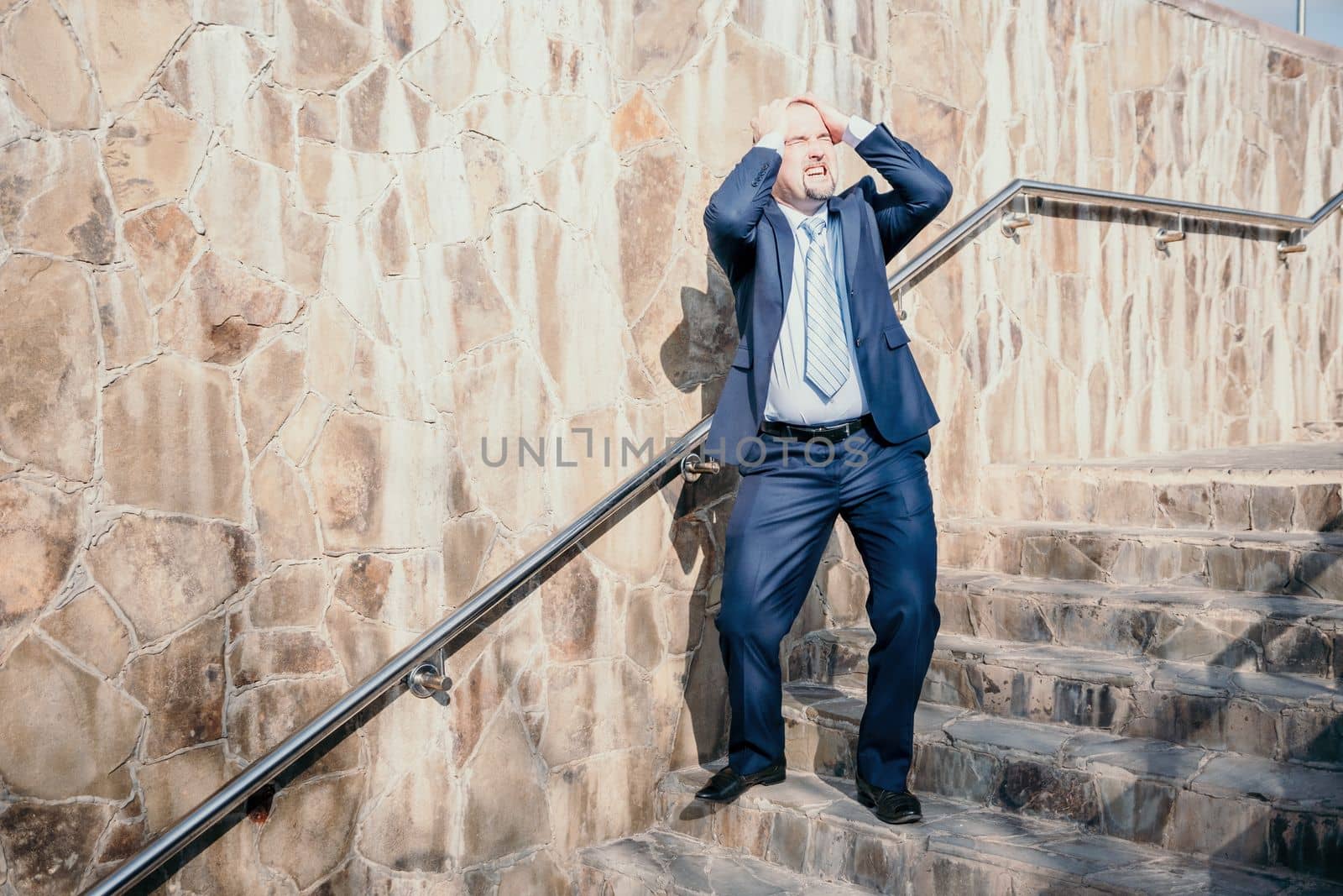 Portrait of a senior professional man in a suit with various problems. A middle-aged businessman with a briefcase descends the stairs.