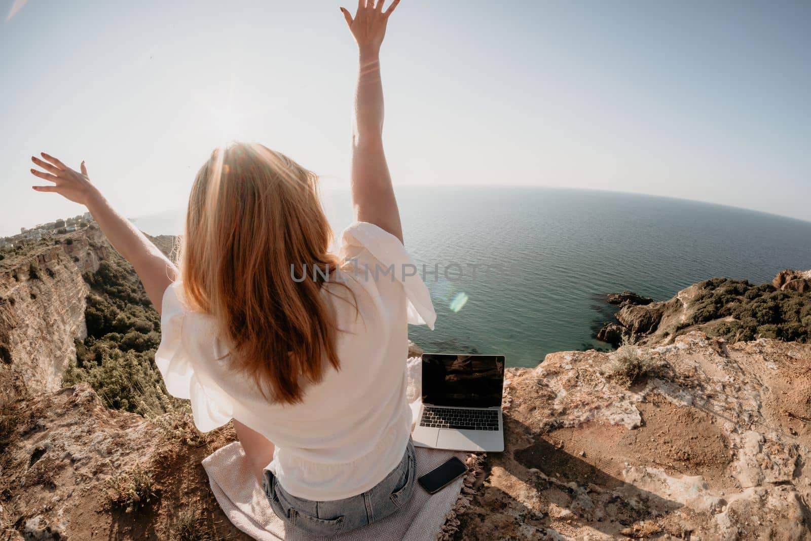 Woman sea laptop. Business woman in yellow hat working on laptop by sea. Close up on hands of pretty lady typing on computer outdoors summer day. Freelance, digital nomad, travel and holidays concept.