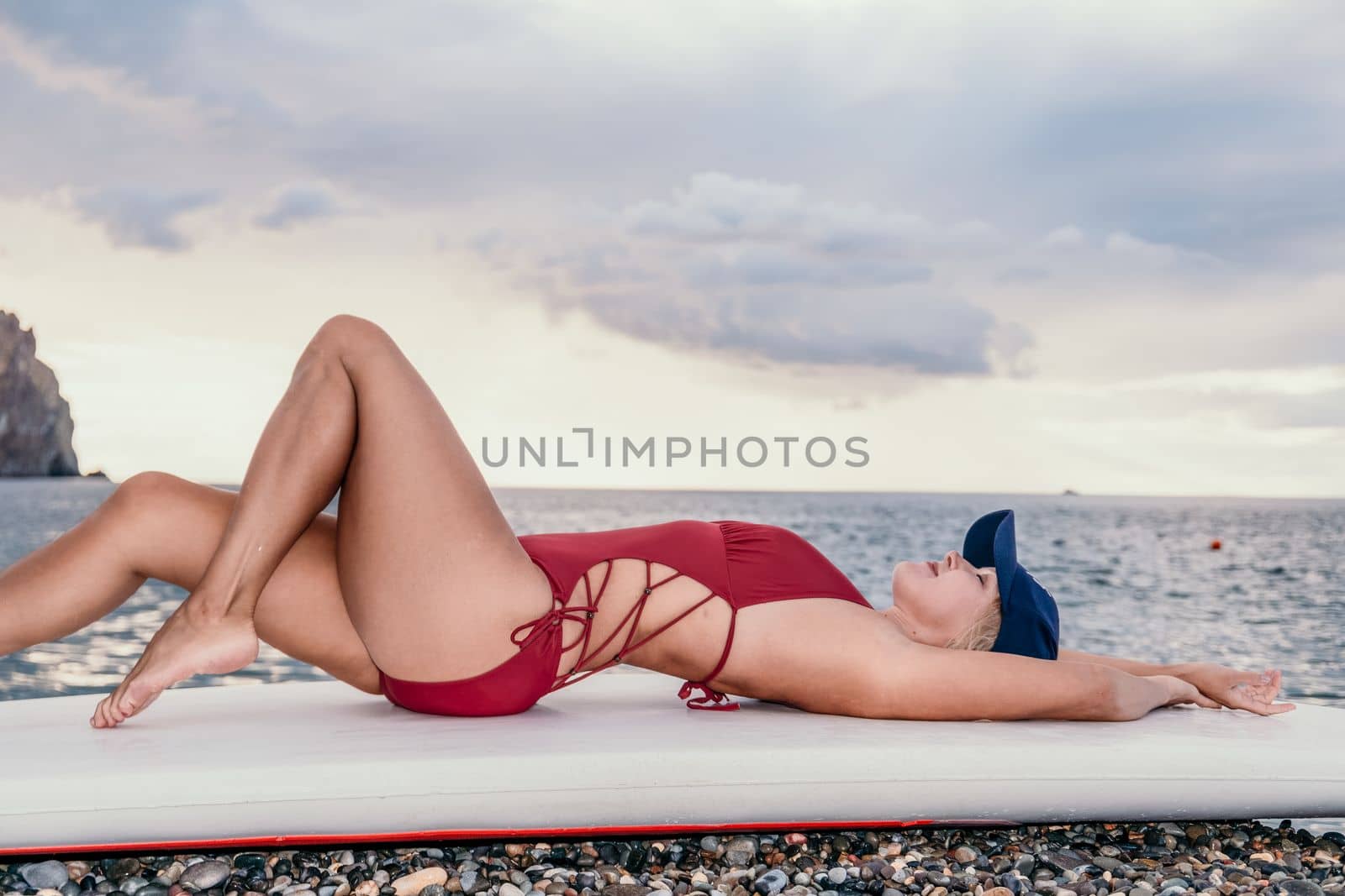 Woman in red bikini on Beach. Happy lady with blond hair in bathing suit chilling and sunbathing by turquoise sea ocean on sunset. Holiday, vacation and recreational concept. Close up by panophotograph