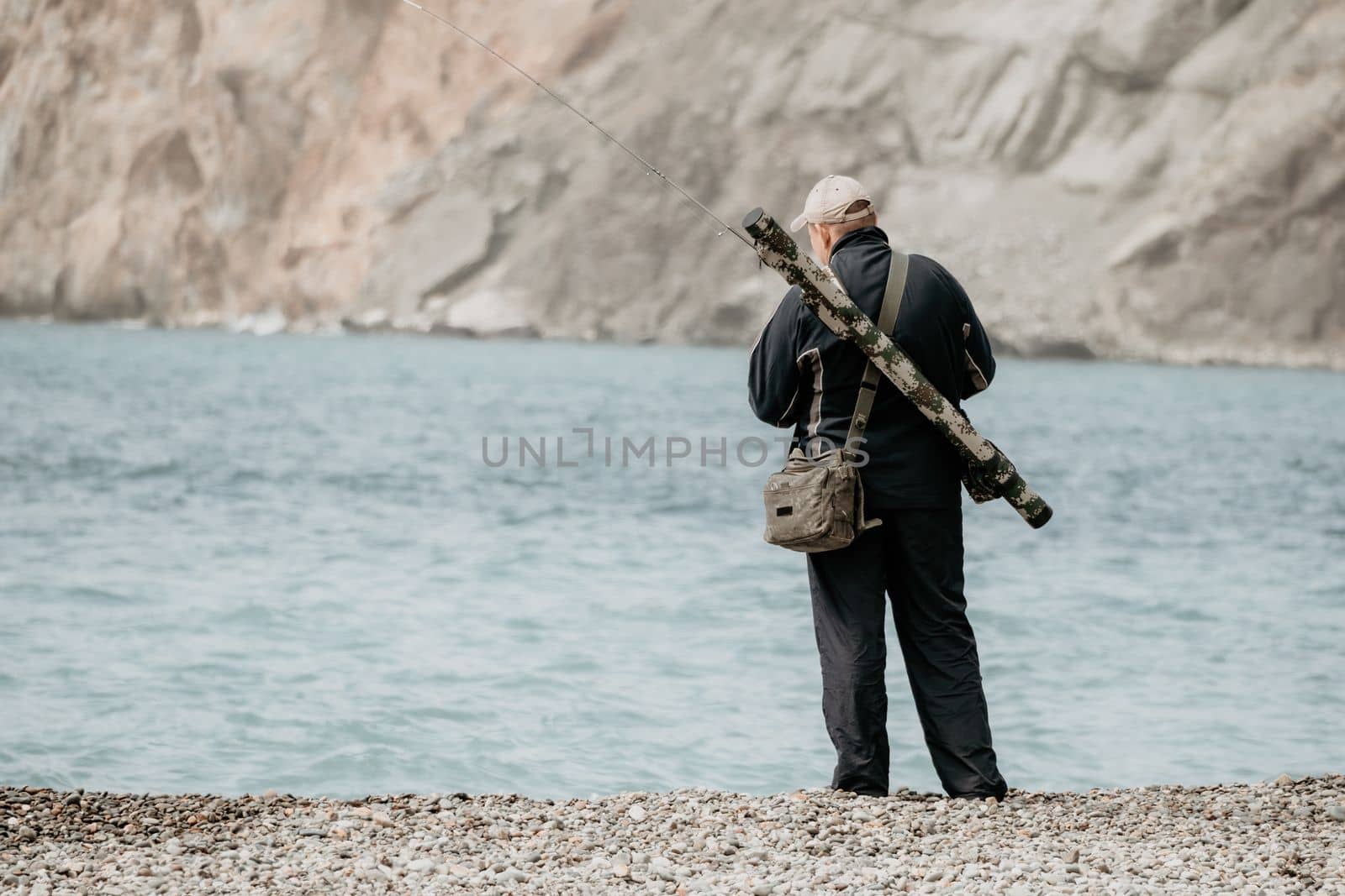 Man hobby fishing on sea tightens a fishing line reel of fish summer. Calm surface sea. Close-up of a fisherman hands twist reel with fishing line on a rod. Fishing in the blue sea outdoors