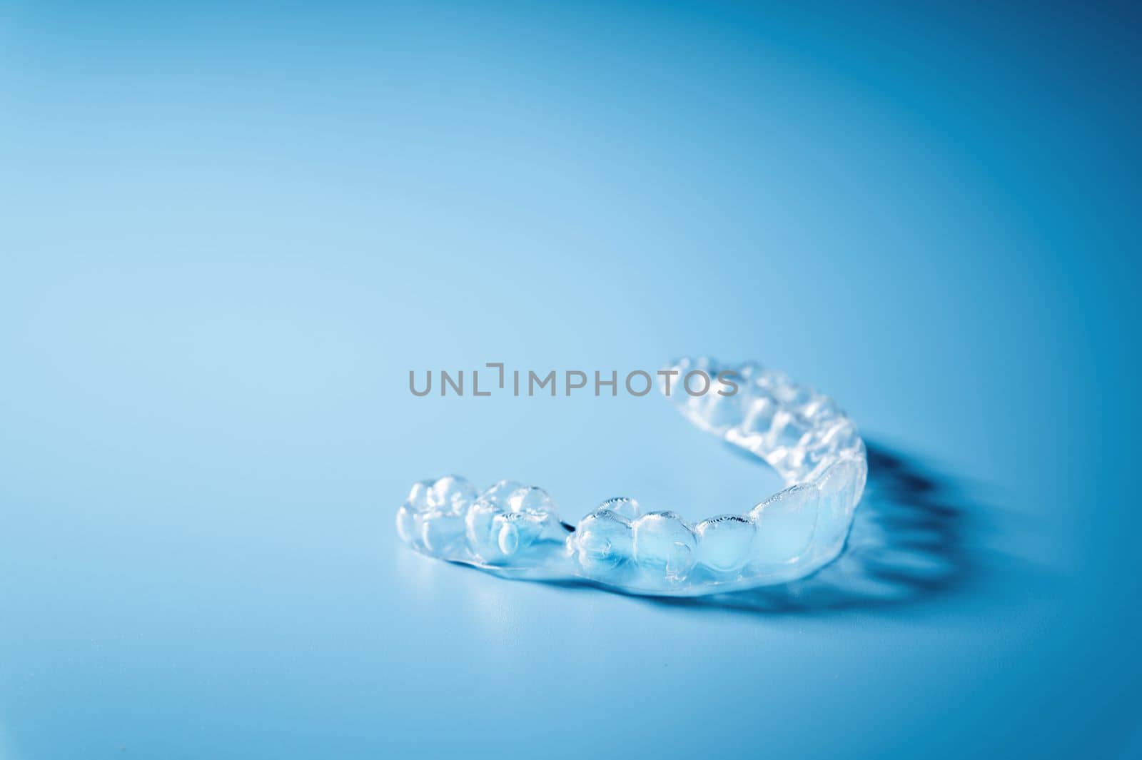 Close up invisible aligners on the blue background with copy space. Plastic braces dentistry retainers to straighten teeth.