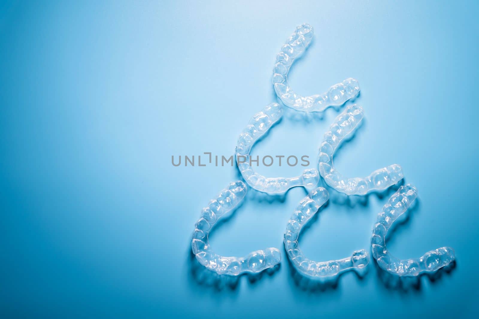 transparent straighteners for teeth in the shape of a pyramid on a blue background, dentistry and orthodontics. 3D printing in modern medicine by yanik88