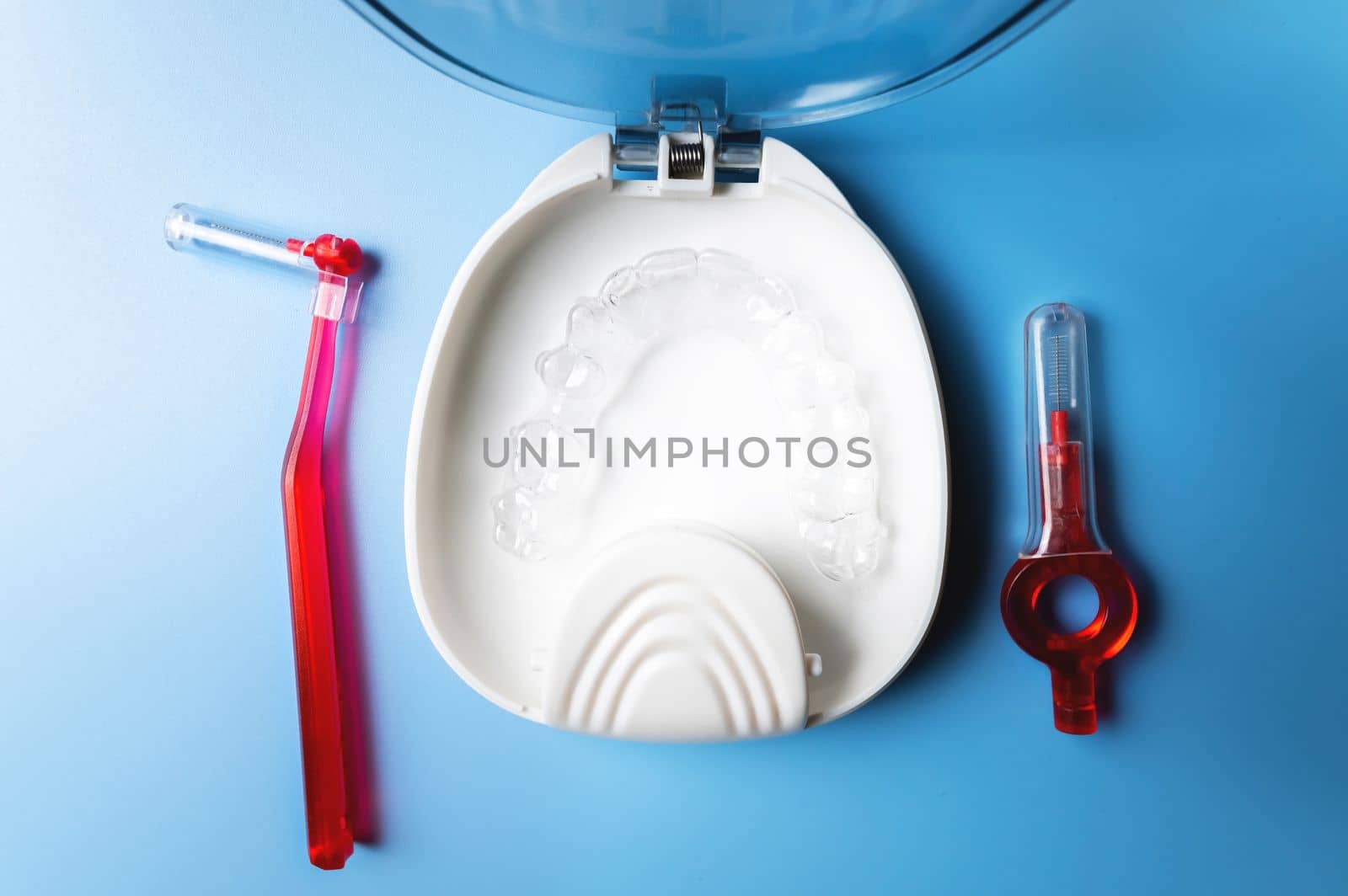 close-up, white box with plastic braces inside and red interdental brush. orthodontic care and cosmetology.