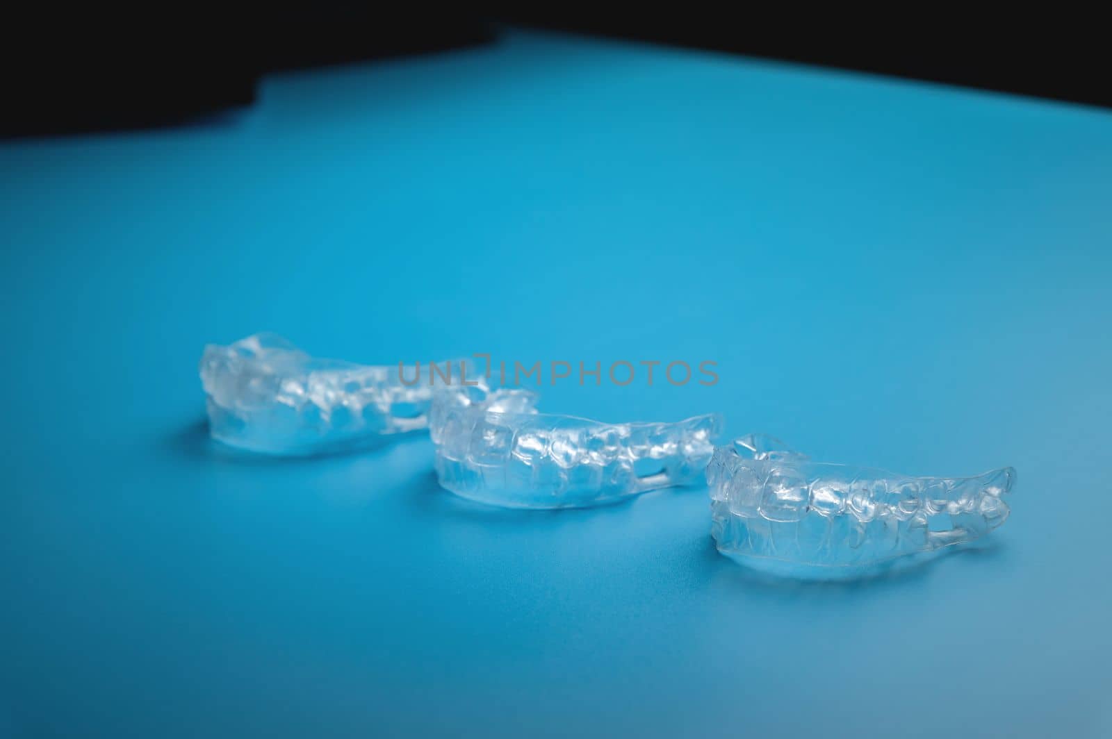 a row of aligners, side view, on a blue background.