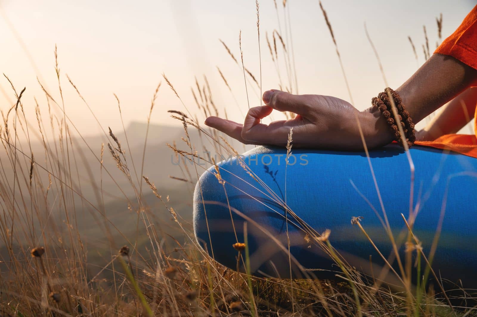 close-up, woman's hand in the lotus position in the grass in the mountains, meditation and relaxation.