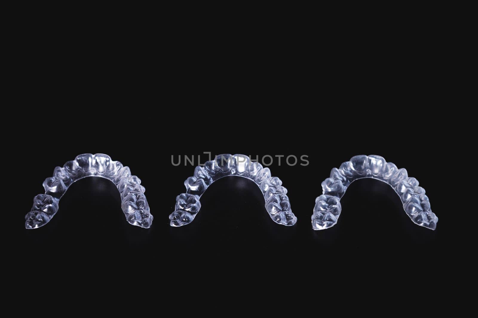 a row of aligners on a black background. modern transparent braces, new care in orthodontics.
