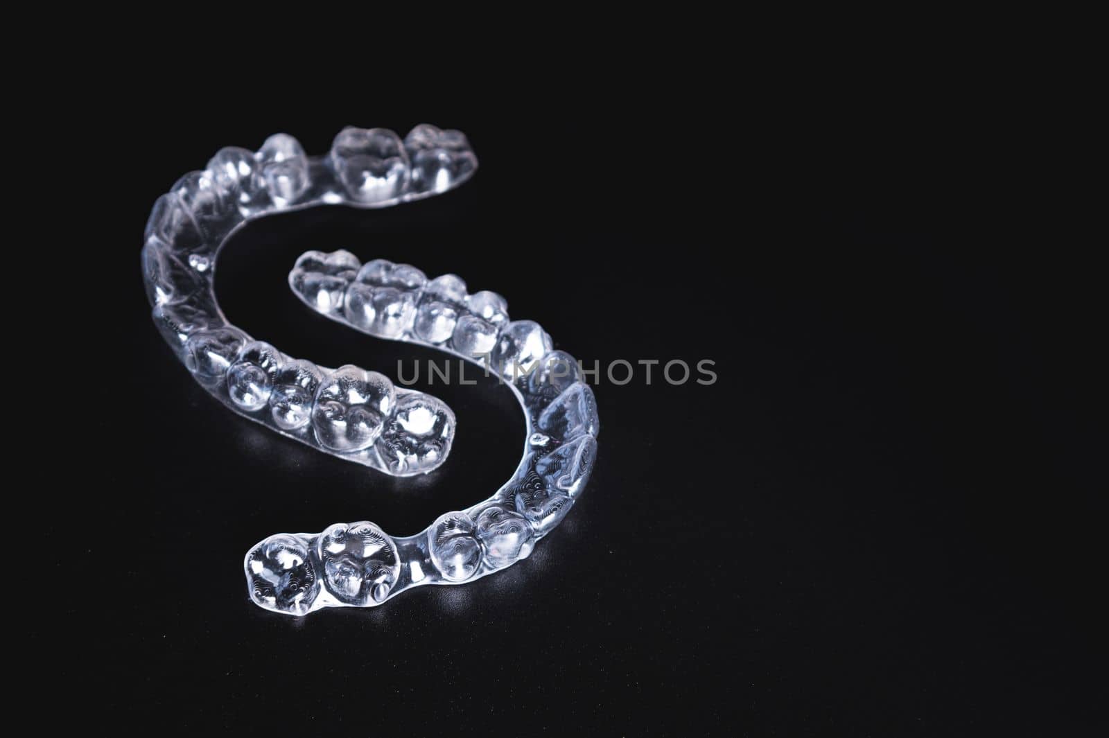 pair of transparent braces lies on a black background. orthodontics, bite correction and cometic dental care by yanik88