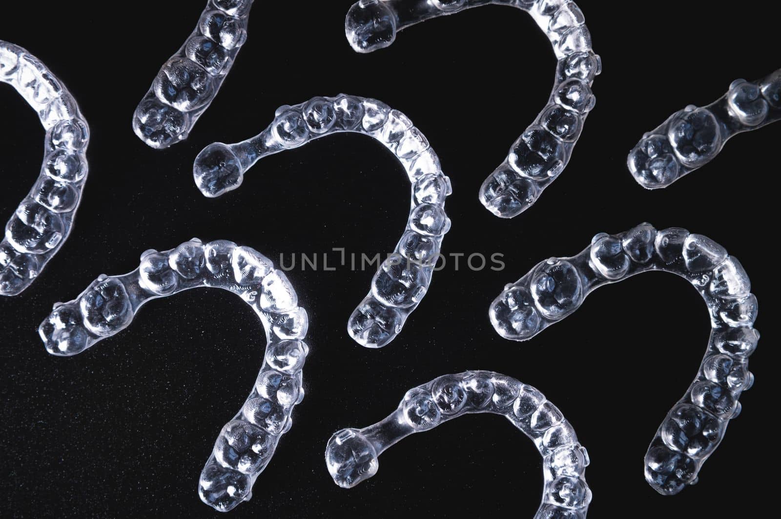 a lot of aligners lie on a black background, studio shot.