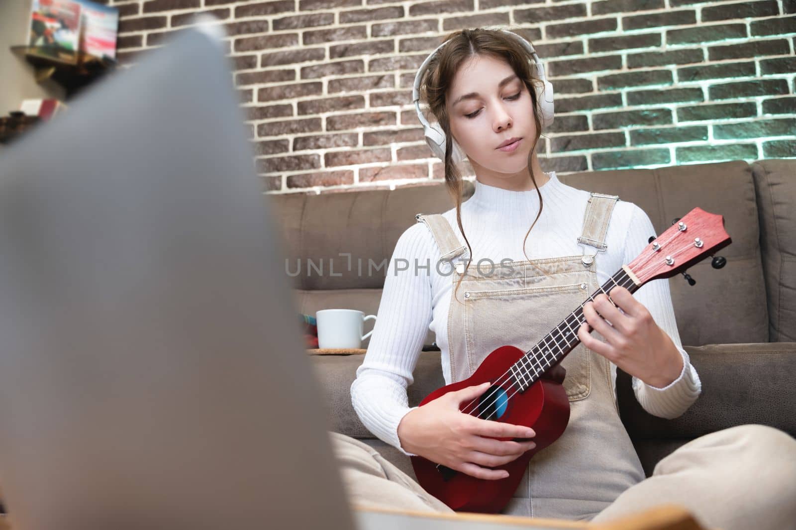 cute girl concentrated on playing the ukulele sitting on the floor at home.