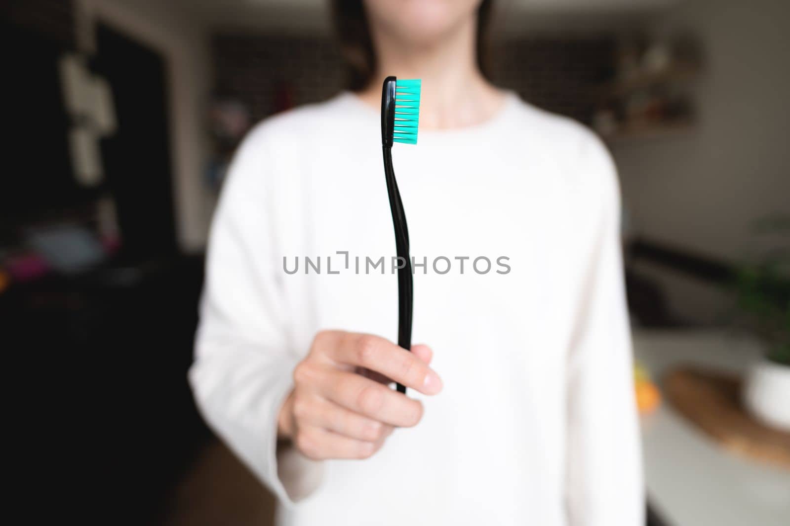 Woman holding a toothbrush in the foreground in focus, blurred background. Oral hygiene.