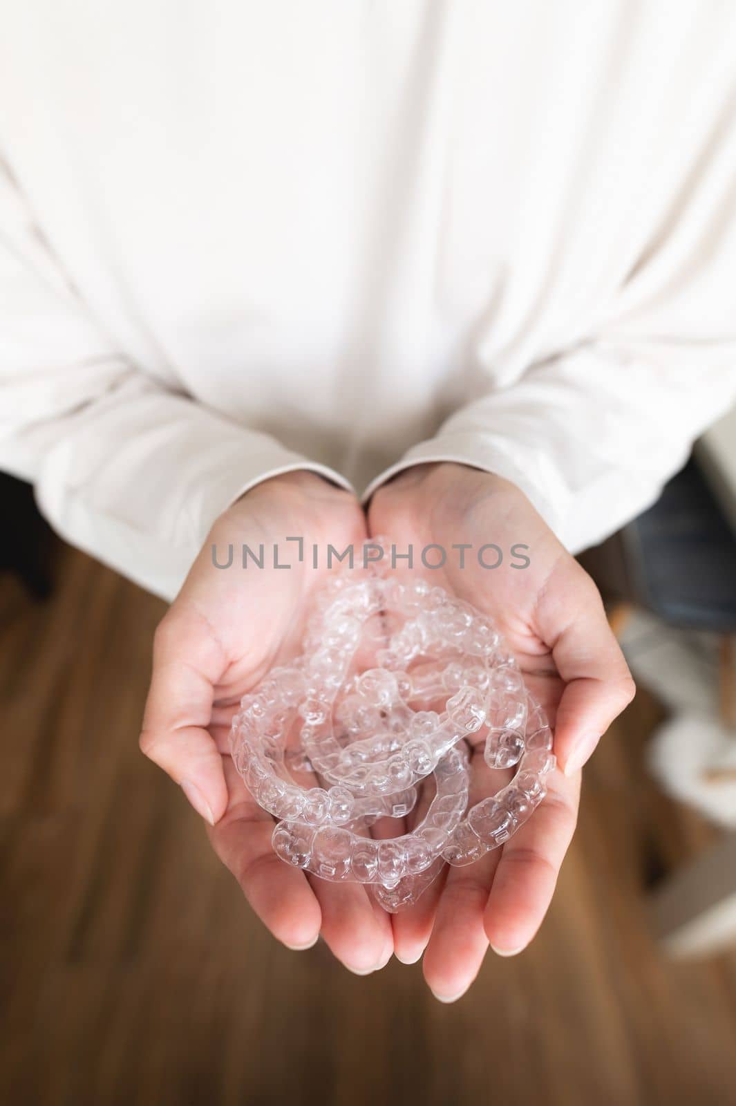 closeup of female hand holding braces at home, dental care and orthodontic concept. blurred background.