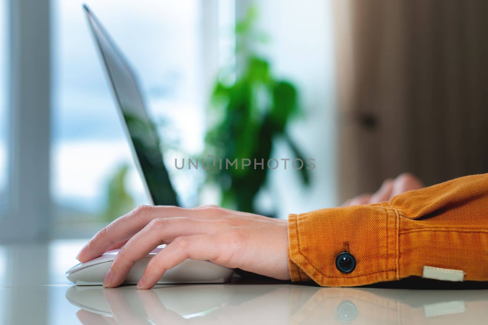 home environment, woman's hand rests on laptop mouse, work from home.