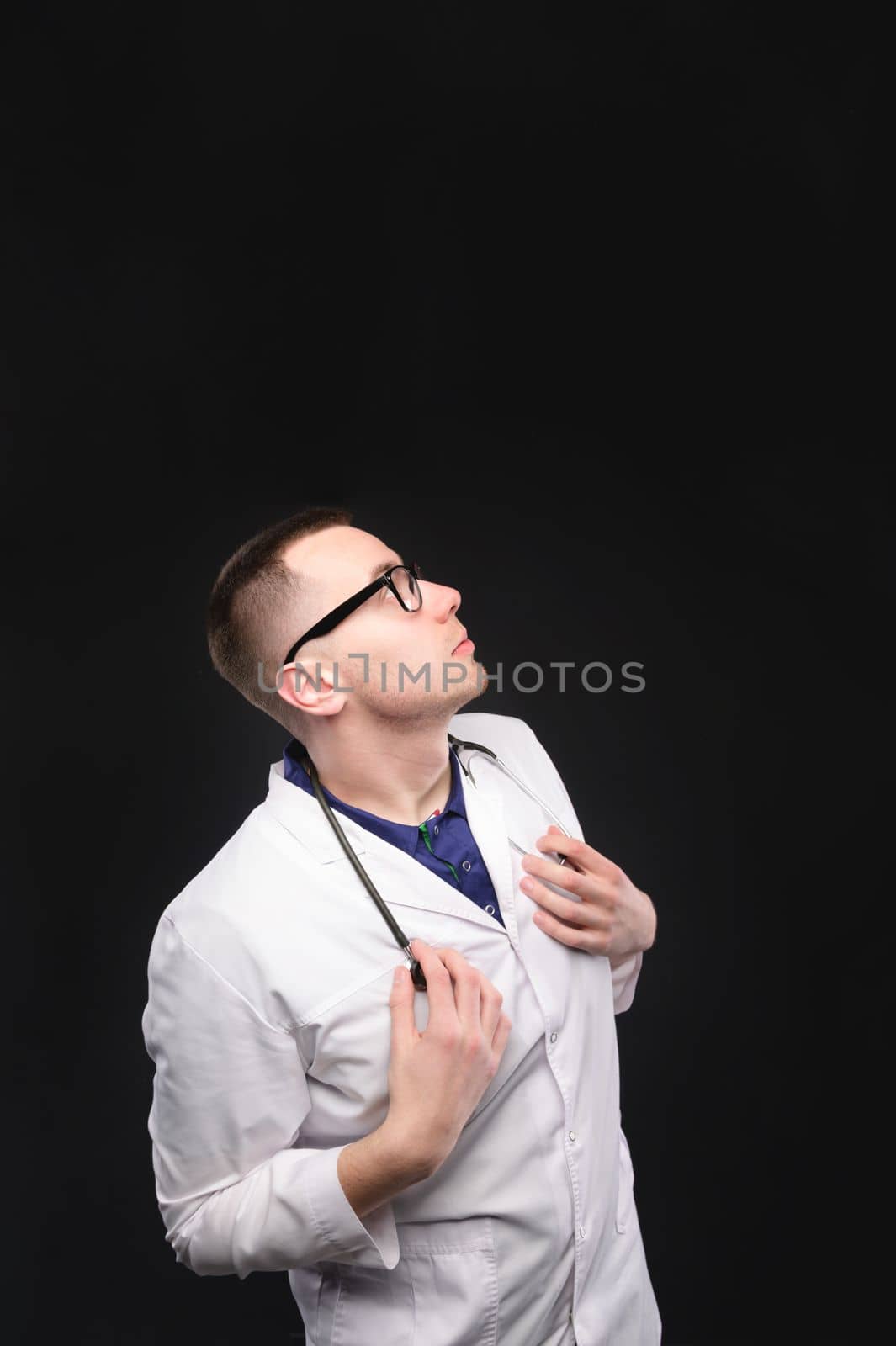 Portrait of a young and attractive doctor in uniform looking up. Concept of request or conversation, dialog box, advertising space.
