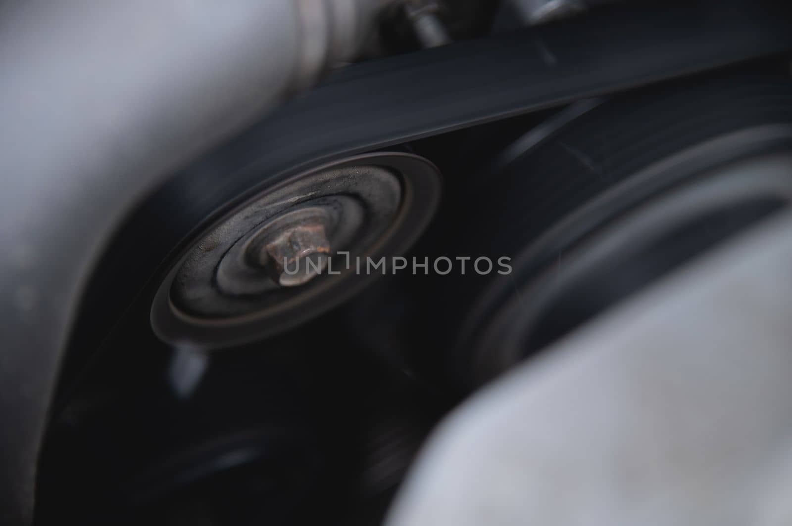 Worn old car engine alternator belt tensioner, close-up.