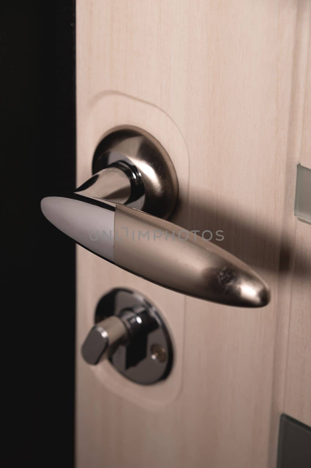 Close up of stylish silver chrome door handle on modern interior door. Stylish light brown door with frosted glass inserts. Concept of catalog of door handles for furniture store by yanik88
