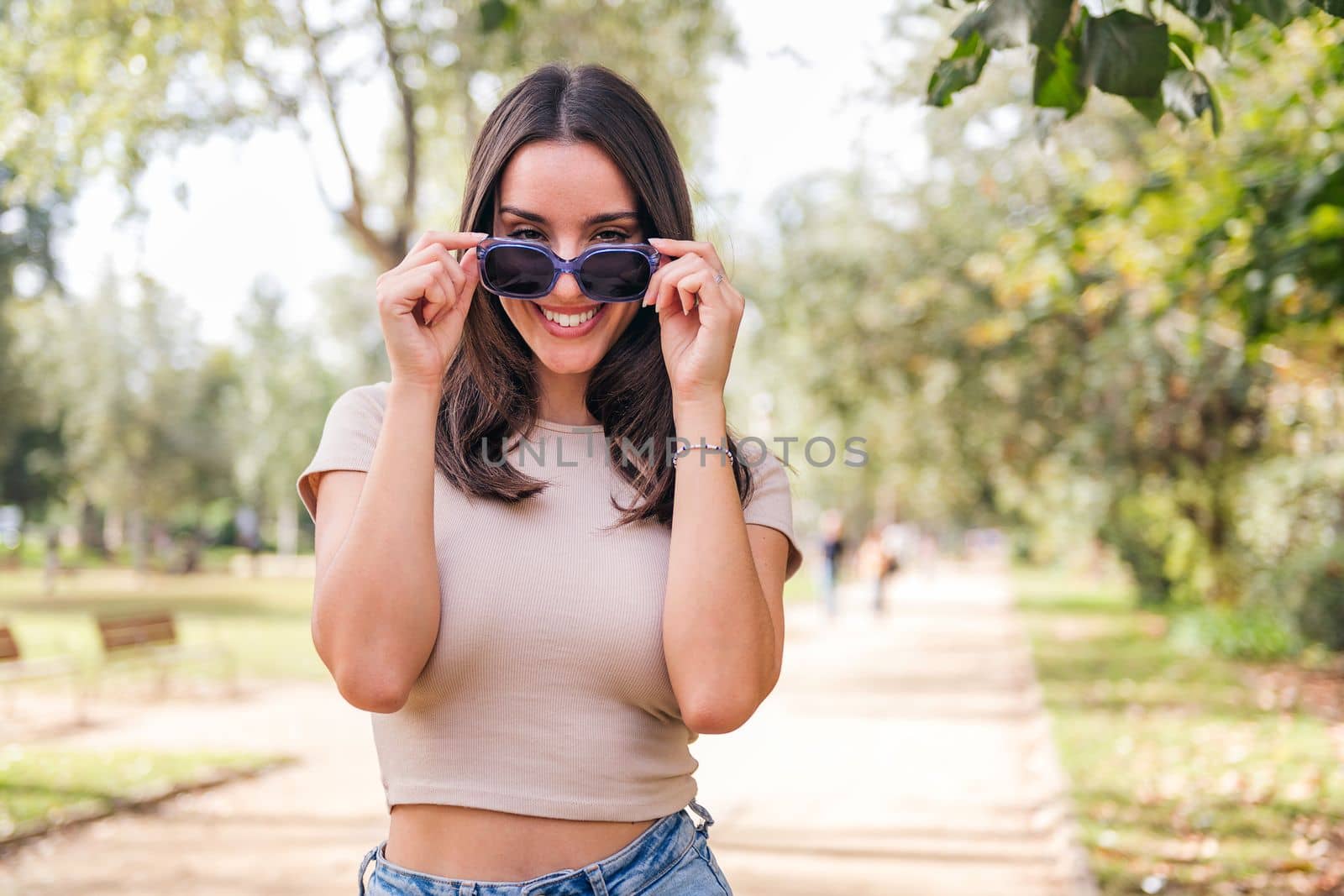 young caucasian woman with a big smile looking at camera over her sunglasses, concept of youth and beauty