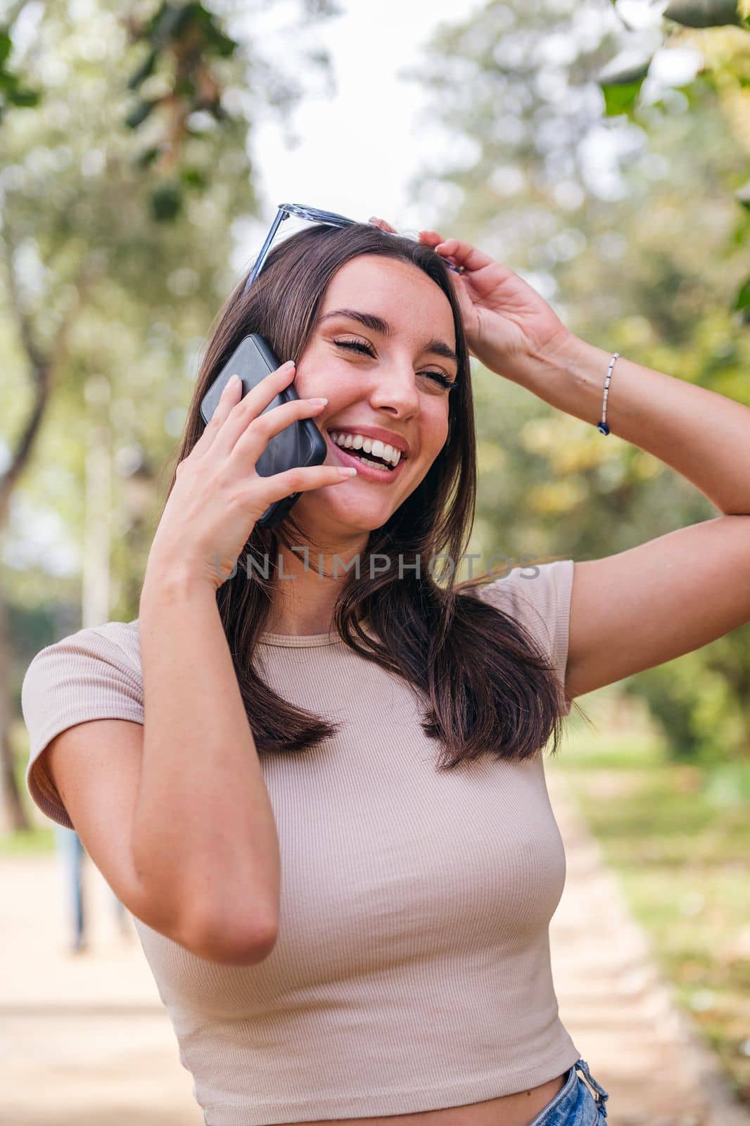 young caucasian woman smiling a call with her mobile phone in a park, concept of youth and technology of communication
