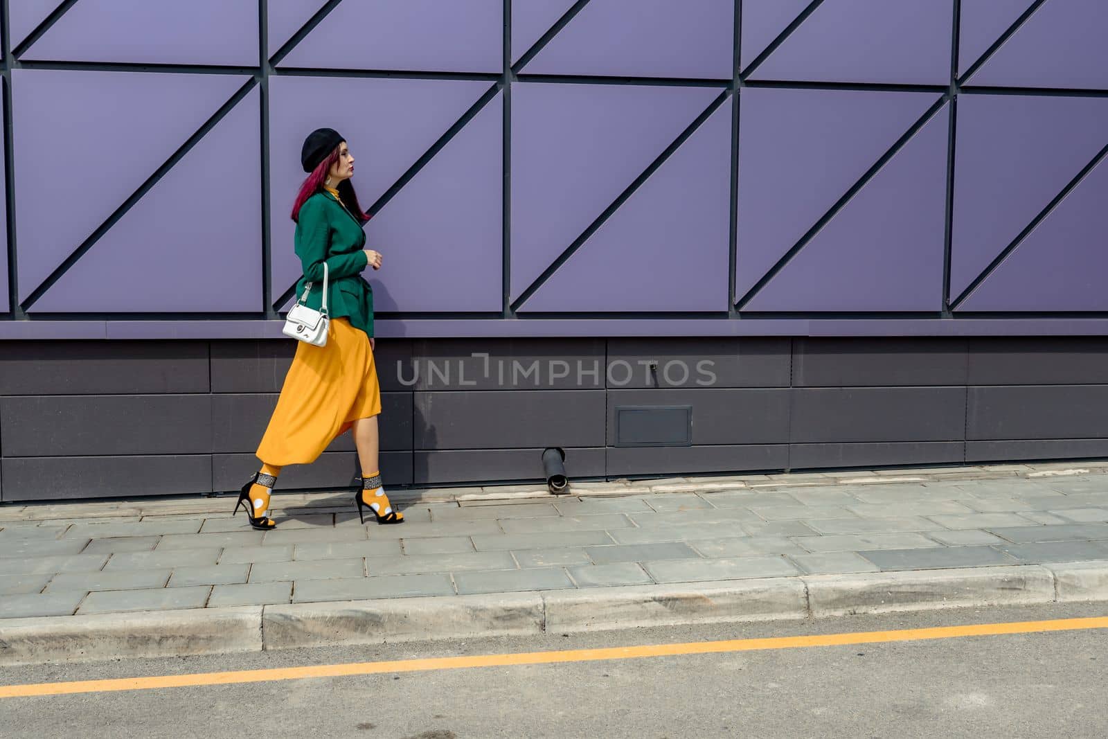woman in bright clothes, yellow skirt and green jacket. Yellow socks in sandals, beret on the head, hair with the color of magenta.