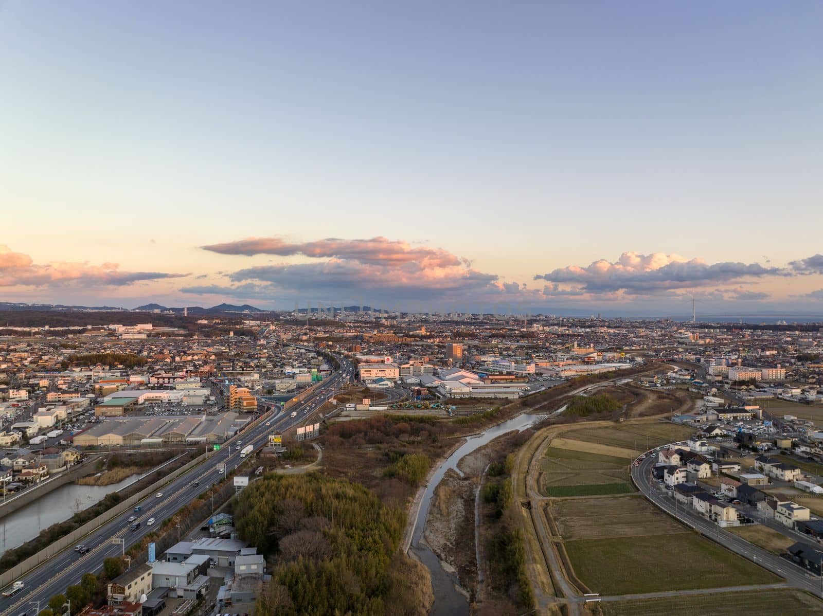 Akashi, Japan - January 30, 2023: Light traffic on highway and roads at edge of sprawling town at sunset by Osaze