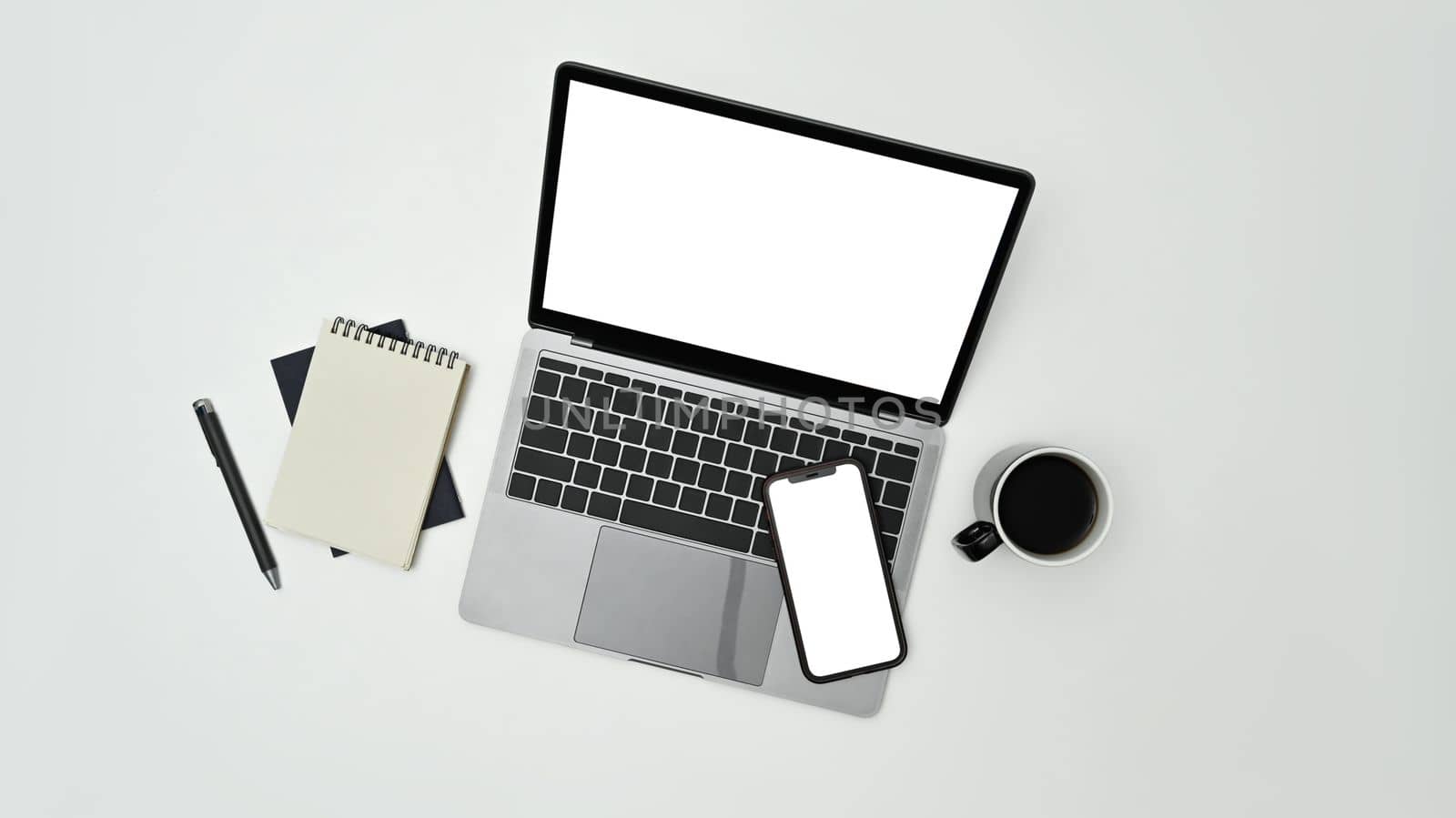 Above view laptop computer, smart phone, notepad and coffee cup on white background by prathanchorruangsak