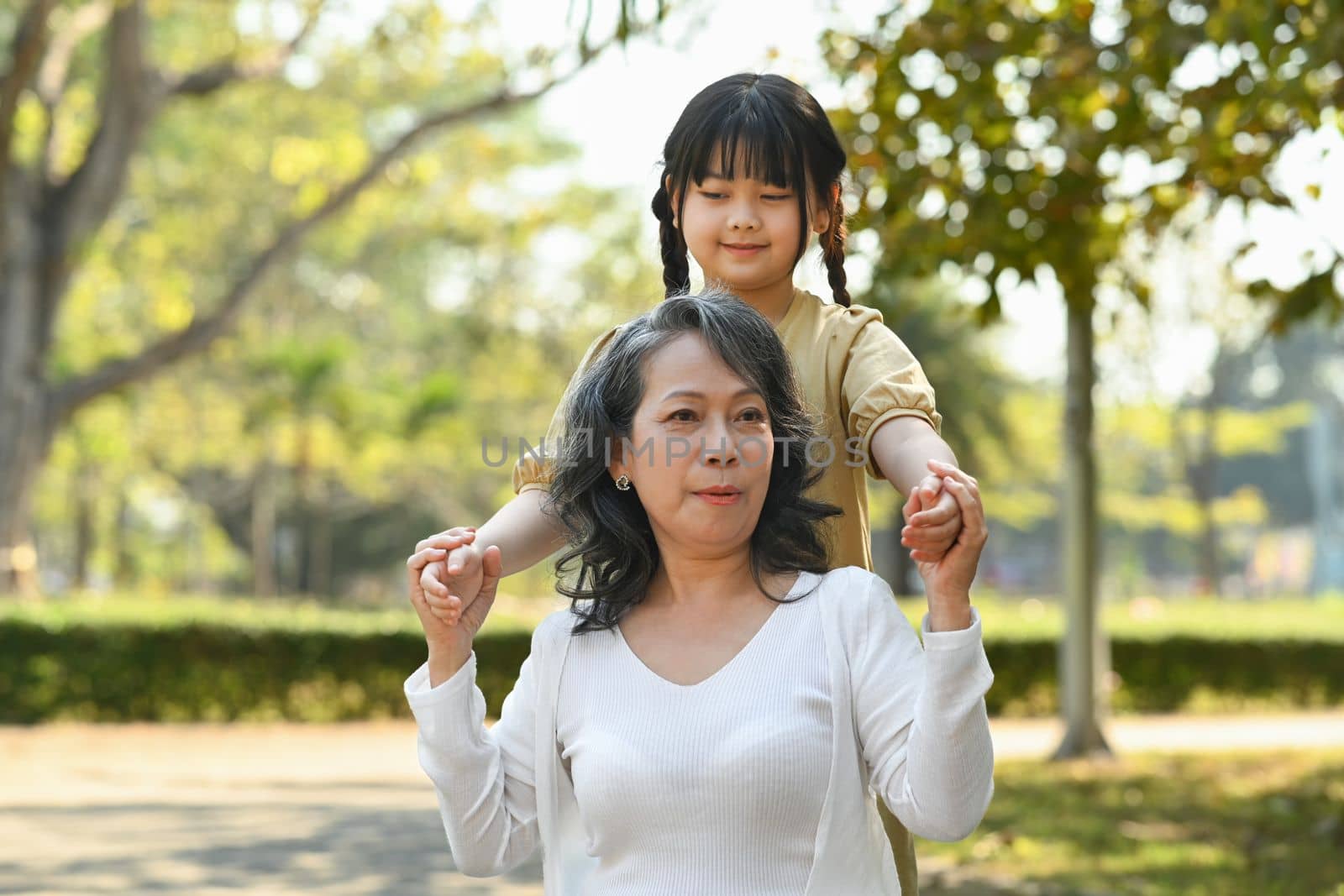 Affectionate middle aged woman and granddaughter enjoying leisure weekend time at outdoor surrounded by nature view.