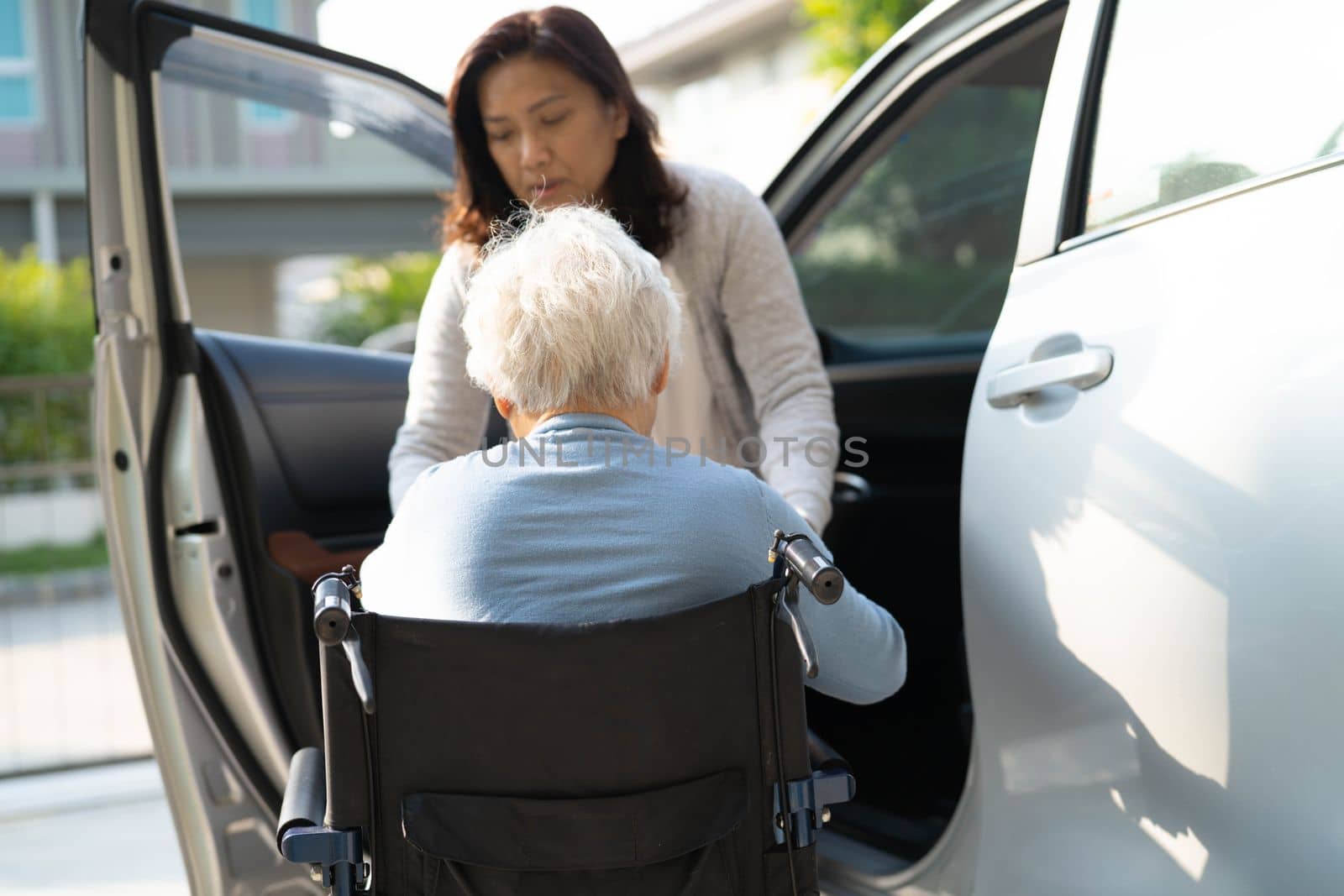 Asian senior or elderly old lady woman patient sitting on wheelchair prepare get to her car, healthy strong medical concept. by pamai