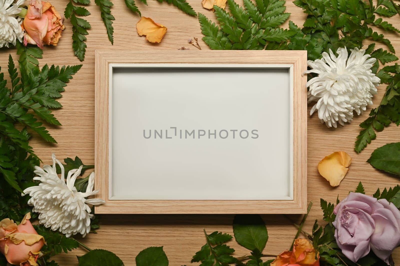 Picture photo frame with real fresh flowers on wooden background. Floral frame and copy space.