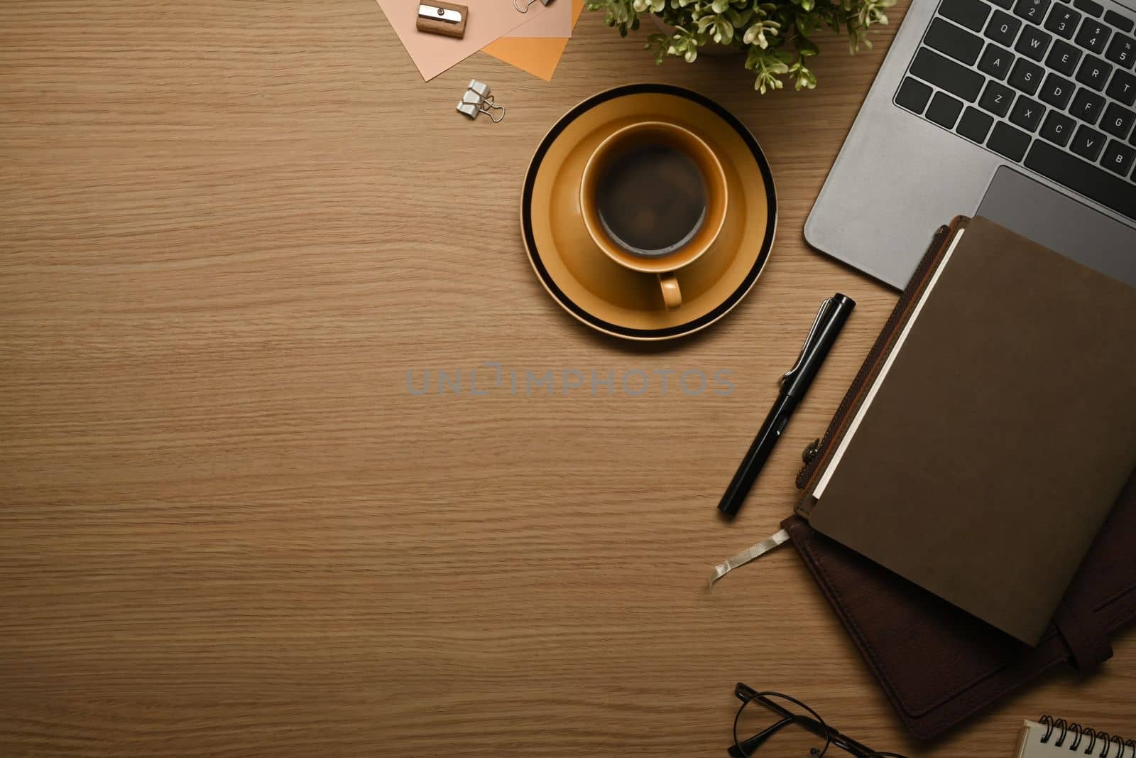 Top view of wooden working with laptop, books, glasses and coffee cup. Copy space for your text by prathanchorruangsak