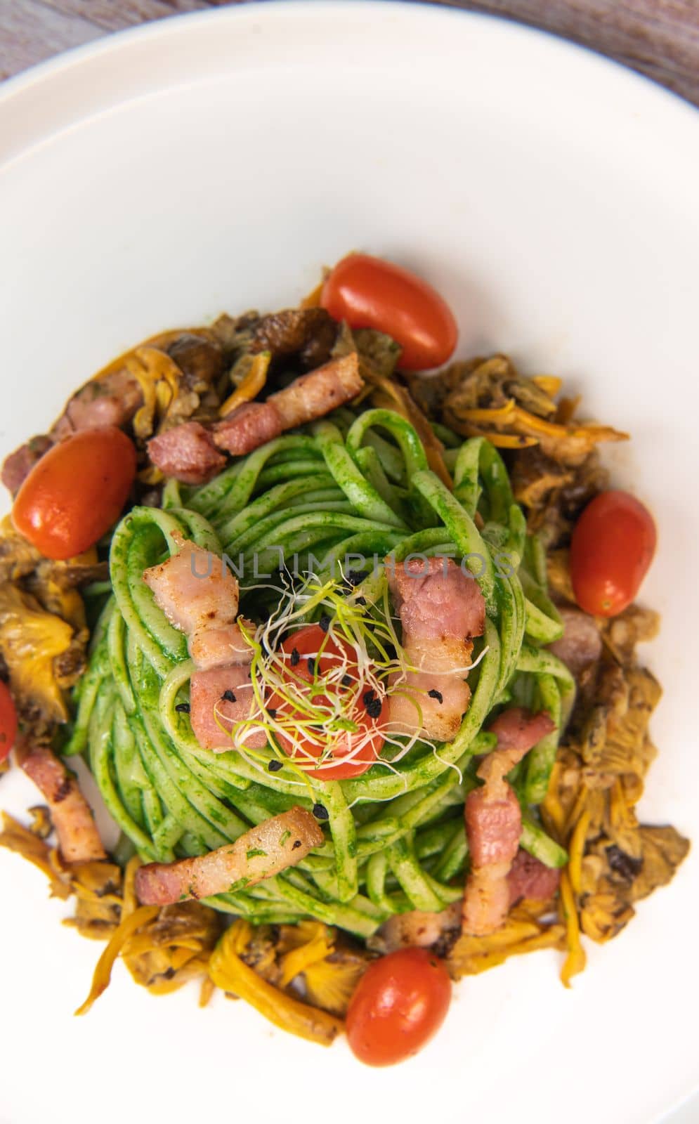Recipe for spaghetti with spinach cream and smoked bacon, tomatoes and chanterelle mushrooms. High quality photo