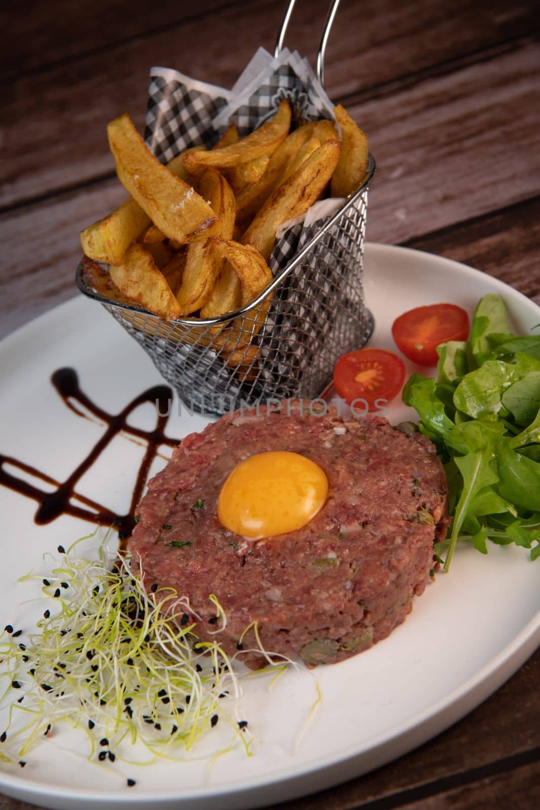 Steak Tartare with vegetables salad and french fries on dish. High quality photo