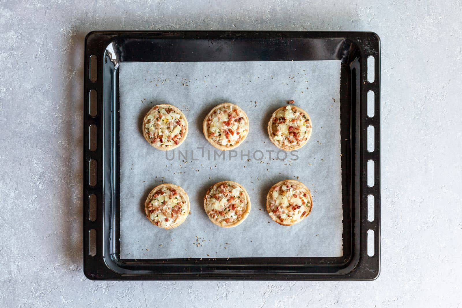 mini Flammekueche, or tarte flambee, french specialty, on the paper on the oven-tray