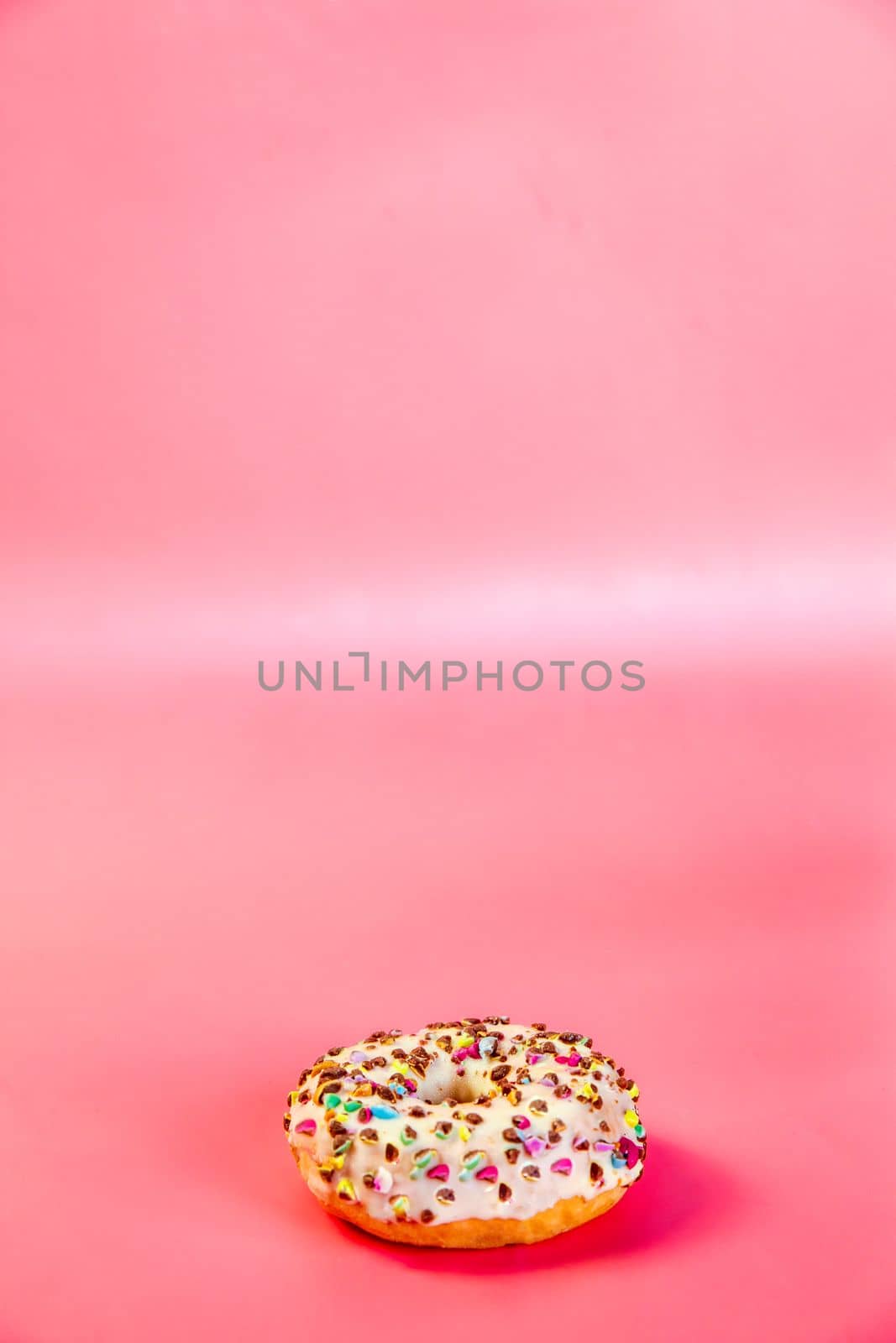 Sweet donuts stacked in a stack on a pink background. Copy space, various glaze and sprinkels chocolate chip, snack fast food sweets concept candy