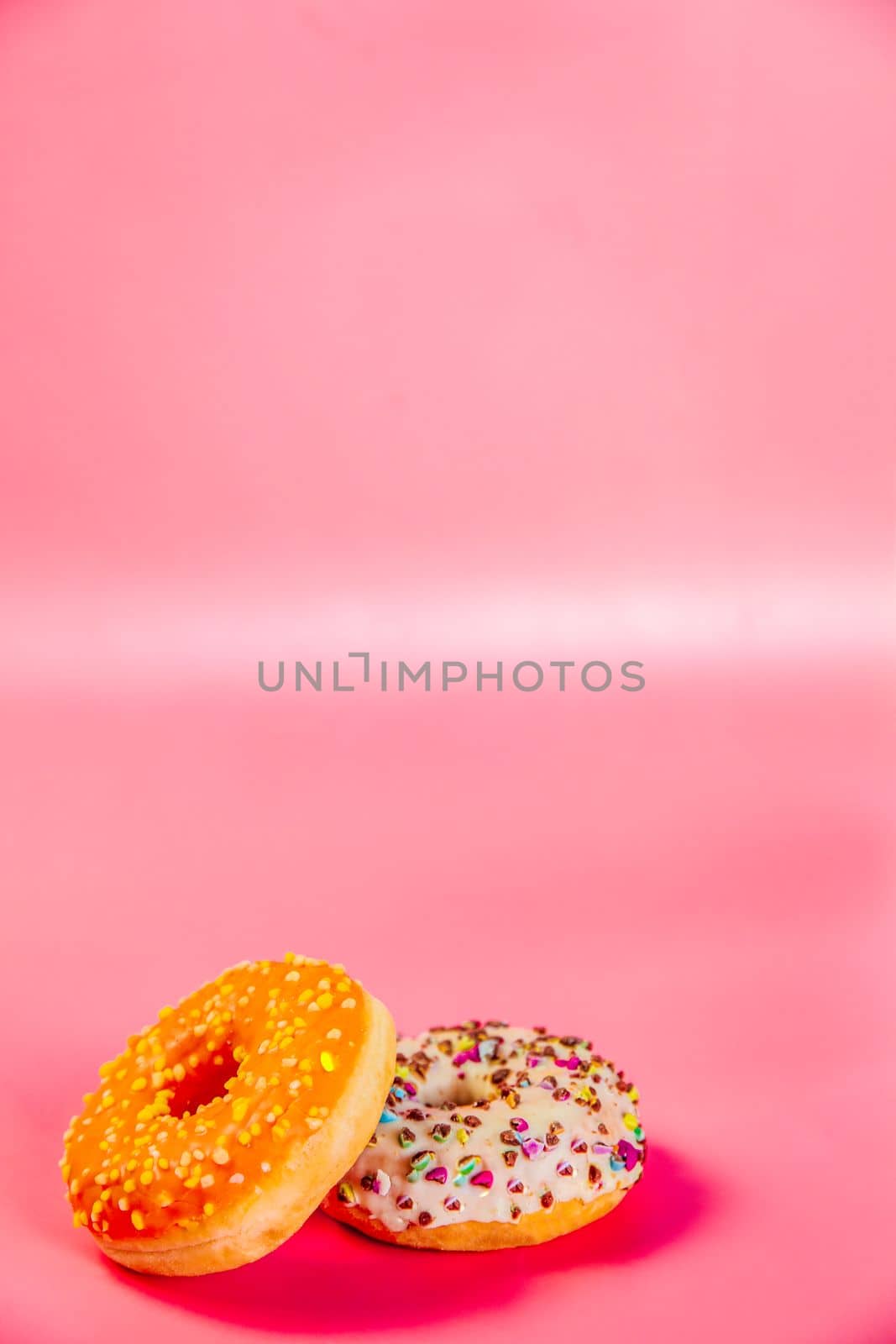 Sweet donuts stacked in a stack on a pink background. Copy space, various glaze and sprinkels chocolate chip, snack fast food sweets concept candy