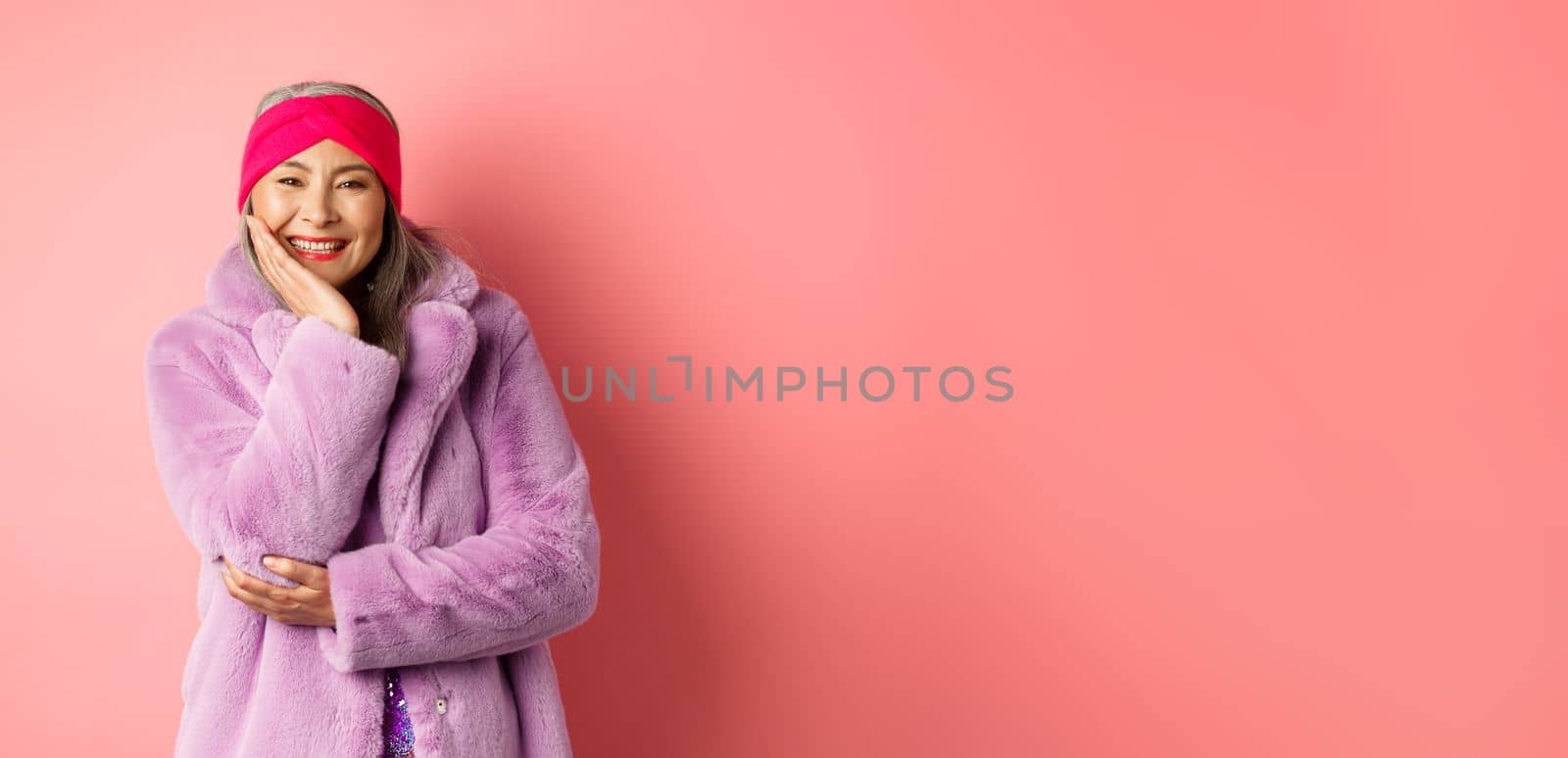 Fashion and shopping. Beautiful and romantic asian mature woman looking caring and heartfelt at camera, smiling happy, standing over pink background.